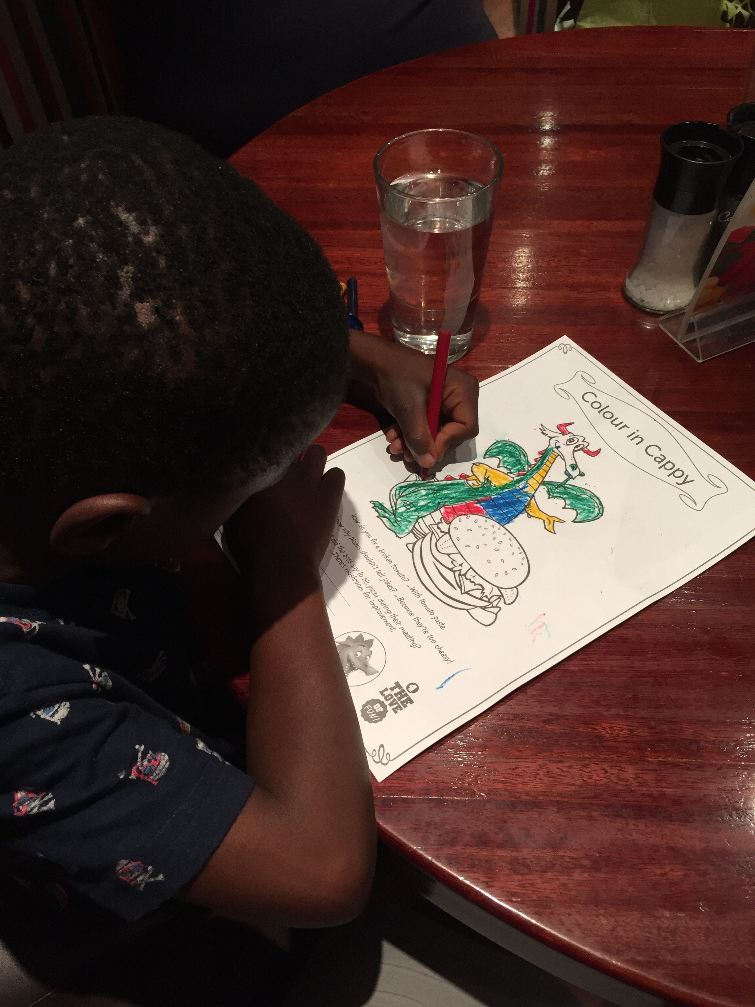 Coloring at dinner. He's wearing a new t-shirt with scuba skull and crossbones. 