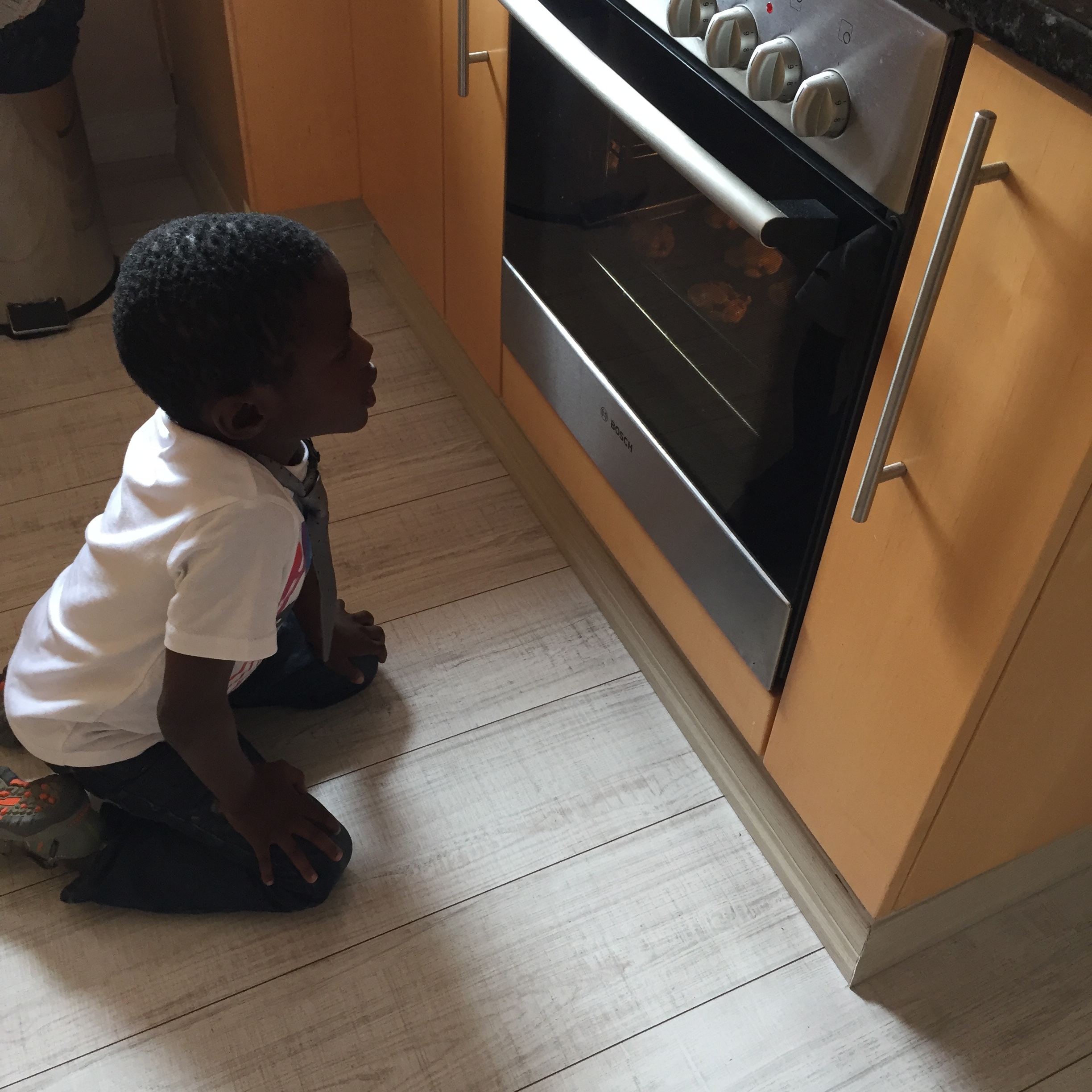 Watching the cookies (he calls them biscuits) bake. In a tie.