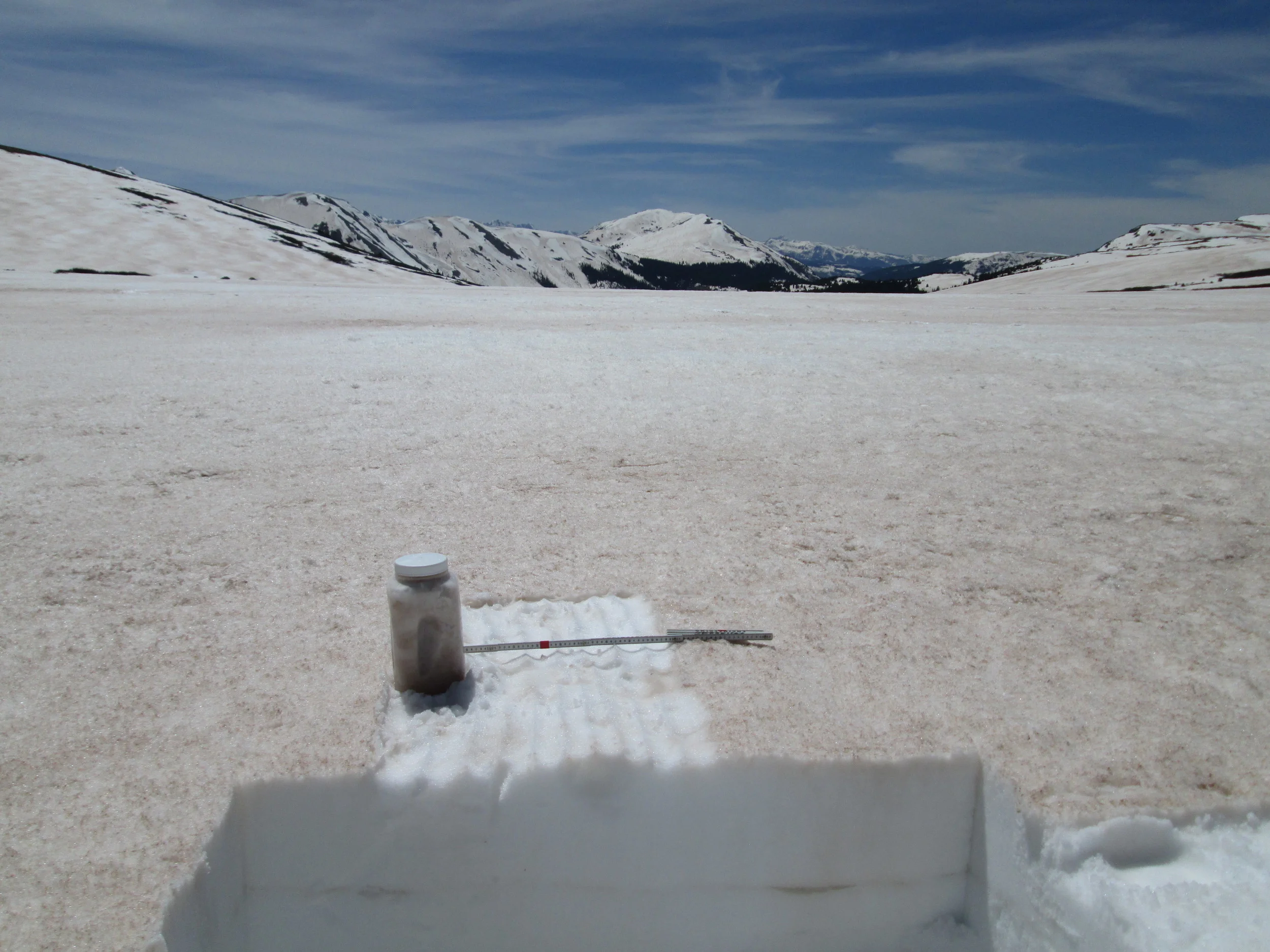 Snowcover was still extensive on the tundra surrounding Independence Pass, here 24” deep. Dust deposition in such alpine terrain exhibits significant spatial variability resulting from wind effects on new snow containing dust., alternately stripping and concentrating dust (and wind-blown snow) in ‘dune’ fields. A typical dune pattern can be seen on the slope on the left, in the distance. An ‘all layers merged’ (ALM) sample was collected in a patch of somewhat higher concentration of dust (than seen just a few yard in the distance), since our purpose with these ALM samples is to facilitate analyses of the dust’s properties rather than to capture a definitive dust mass loading sample. Representative mass loading samples require a well-sheltered site, such as our own Swamp Angel Study Plot at Senator Beck Basin, where wind effects are minimized.
