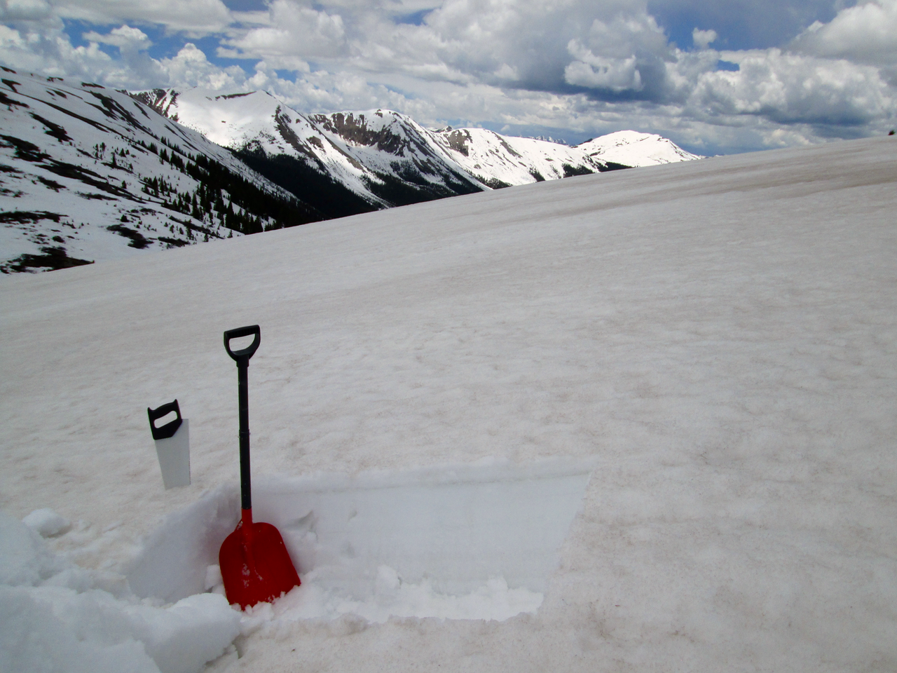 Most snow covered terrain in the Independence Pass locale displayed the kind of dust intensity seen in this photo, showing the merged dust layer in a space between the scattered ‘dunes’ of more concentrated dust seen in the photo above, and in the distance in this photo. The dark band below the snowpack surface is a layer of ice stained by infiltrating melt water containing very fine dust particles. 