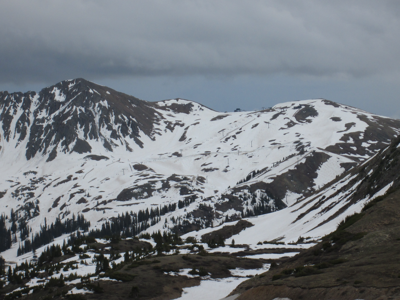This view on June 16, 2015 of the upper Arapahoe Basin ski area, recently closed, clearly shows the concentration of Colorado Plateau dust in patches produced by wind drifting during wet dust-in-snow deposition on lee slopes, where blowing new snow containing dust decelerates and deposits.
