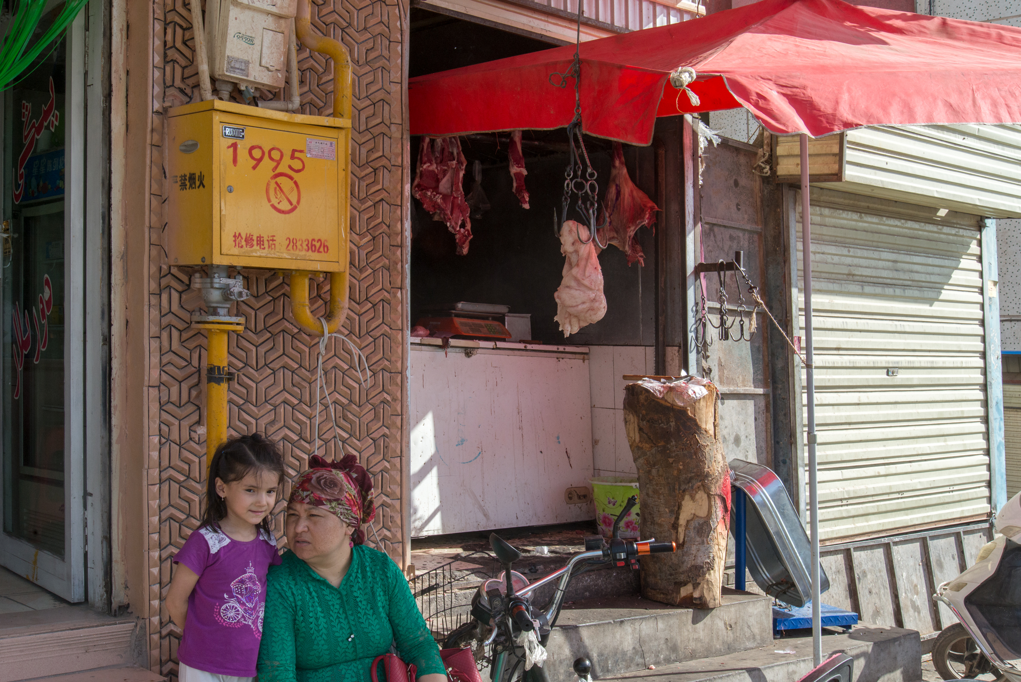 Grandma and Granddaughter in front of butcher shop, Kashgar Baazar