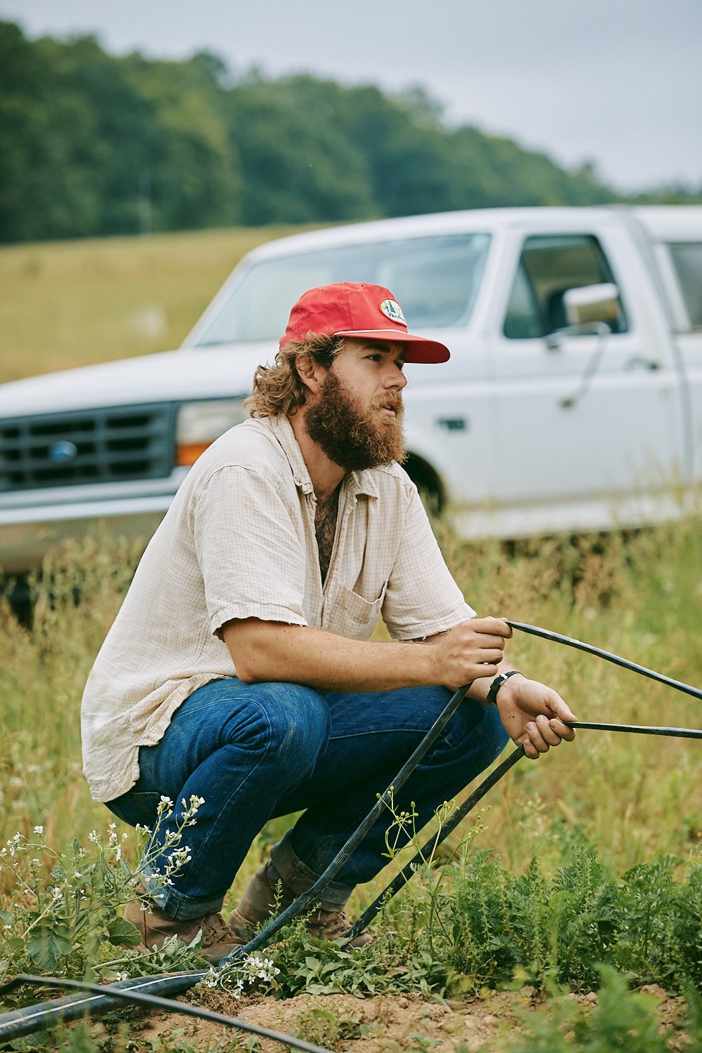 Lifestyle commercial photograph of a farmer checking drip tape on at a farm in North Carolina, shot by photographer Ian Mahathey