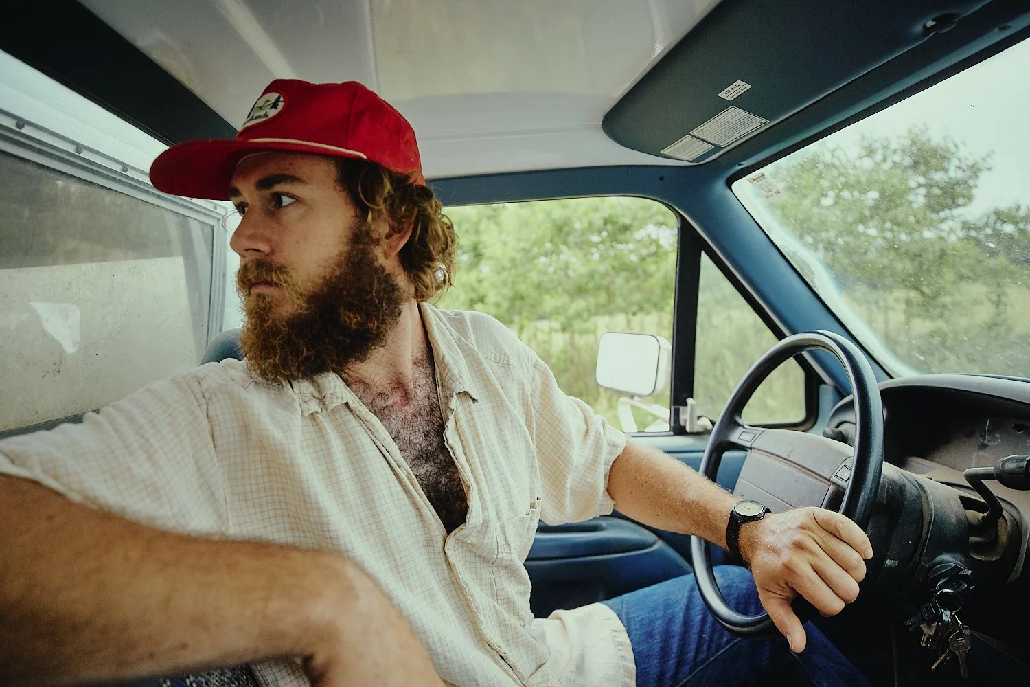 Lifestyle commercial photograph of a man driving a farm truck shot by photographer Ian Mahathey.