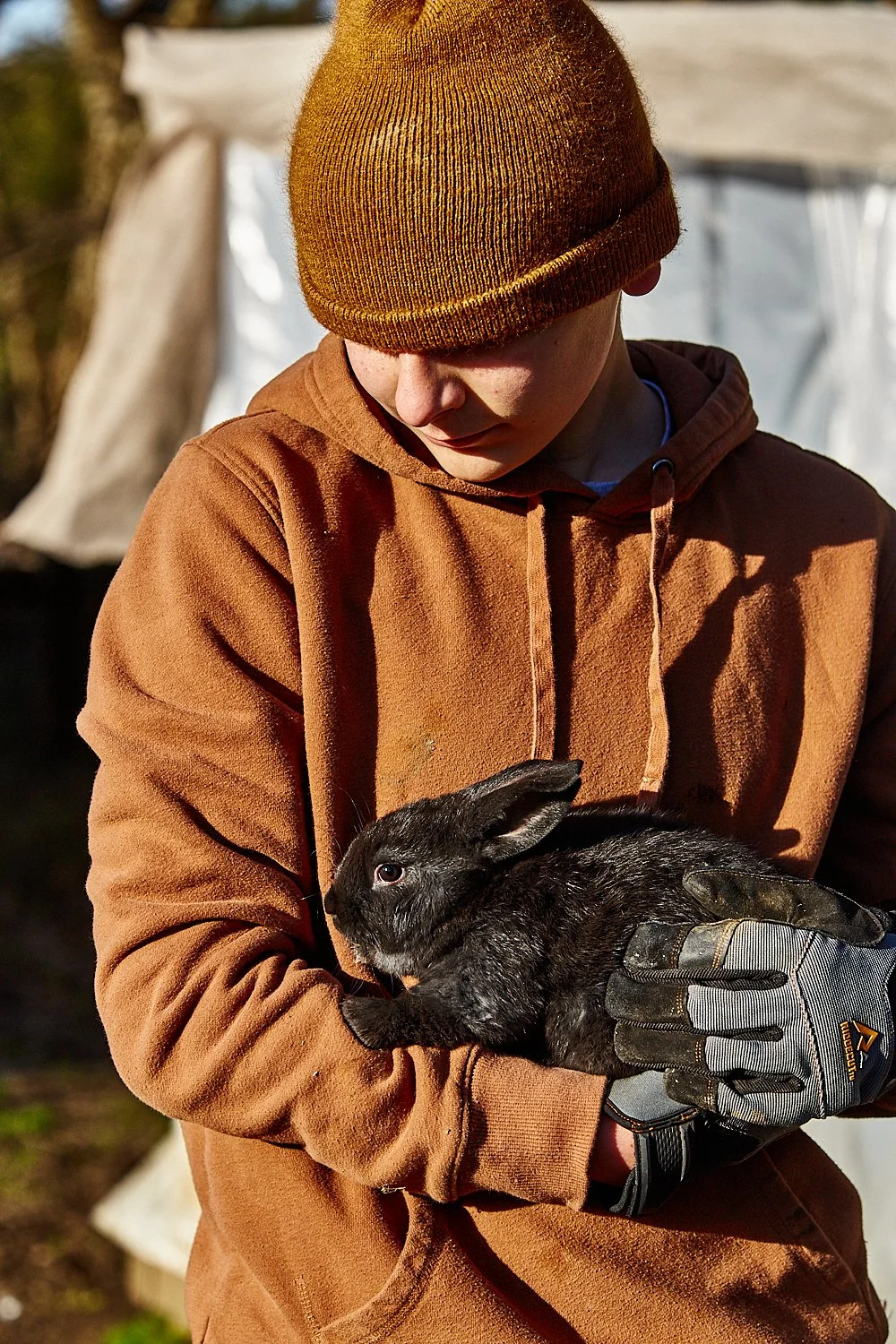 Lifestyle commercial photo of a teenage boy holding a rabbit on a farm in South Carolina, shot by photographer Ian Mahathey.