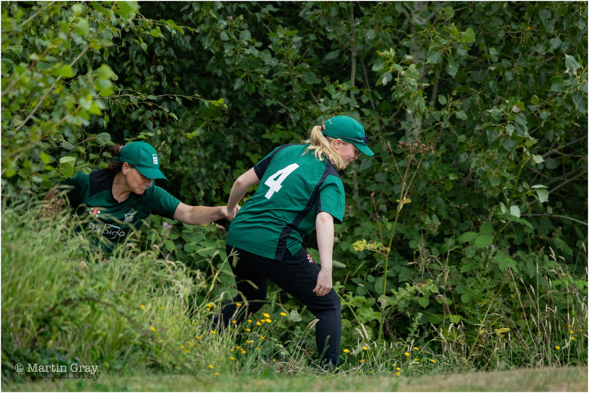 Guernsey's Eva Bourgaize helps Claire Davies out of the undergrowth after retreieving a lost ball-4196.jpg