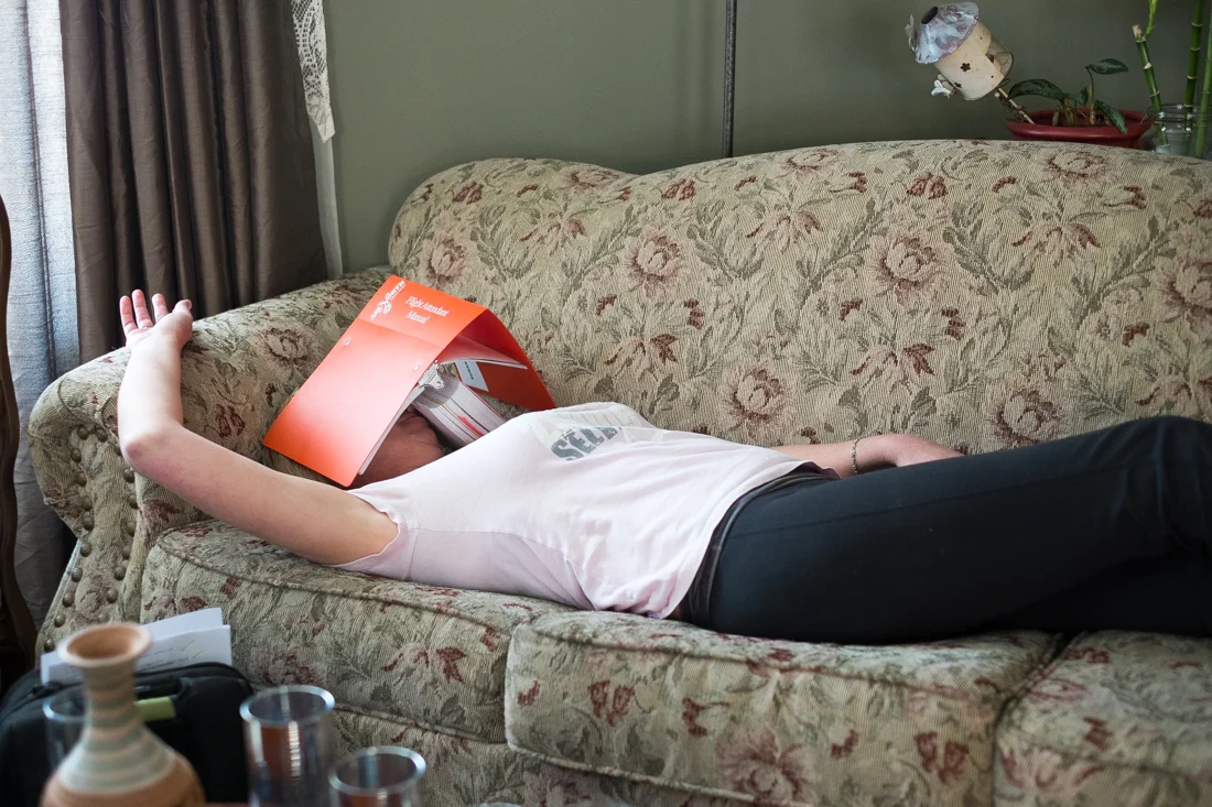Susan Burton has actually been found asleep on the couch with the FAM (flight attendant manual) before. Here she re-creates the visual. Photo by Christa Galloway.