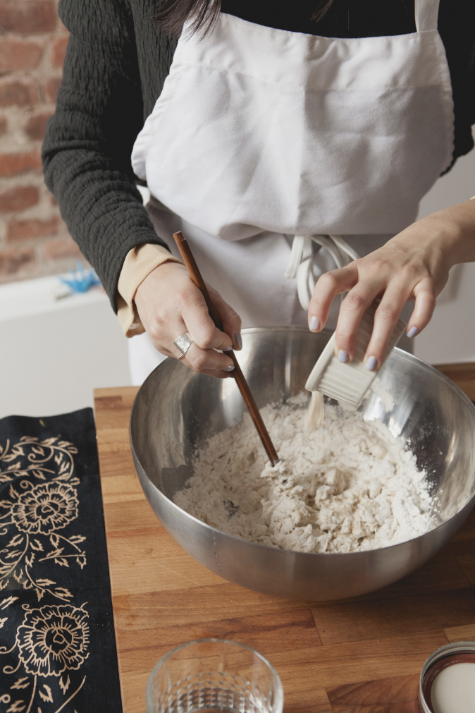 MIxing in water, yeast, sugar, and sugar into the flour. 