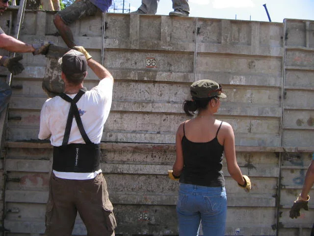 Volunteers pour cement into forms, and the walls of the clinic begin to take shape.