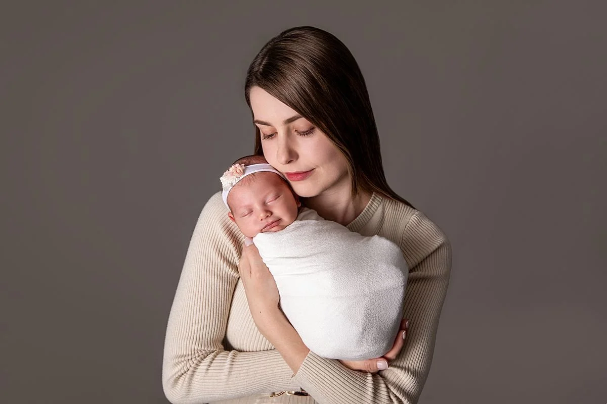 Mom holding sleeping swaddled newborn cheek to cheek , Sarah Kane Photography