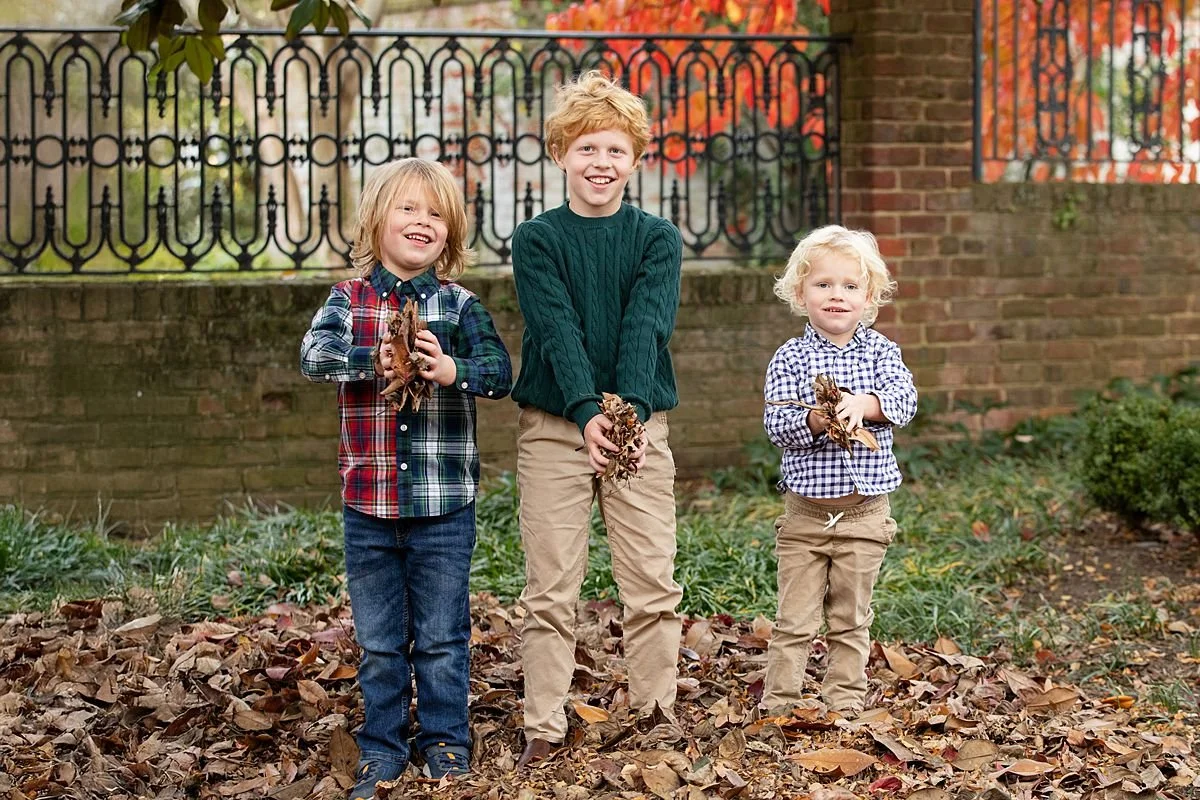 Three young brothers posing with autumn leaves during fall family portraits in Richmond Virginia | Sarah Kane Photography