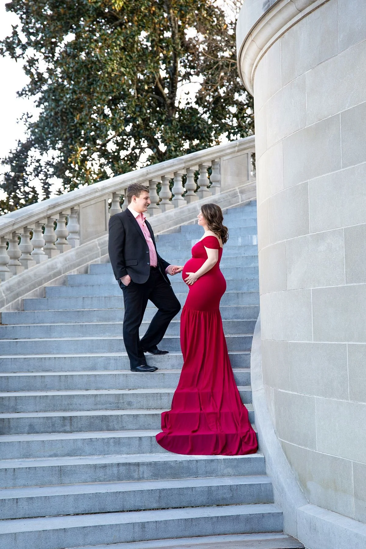 Expecting couple holding hands looking at each other on a grand staircase, Sarah Kane Photography