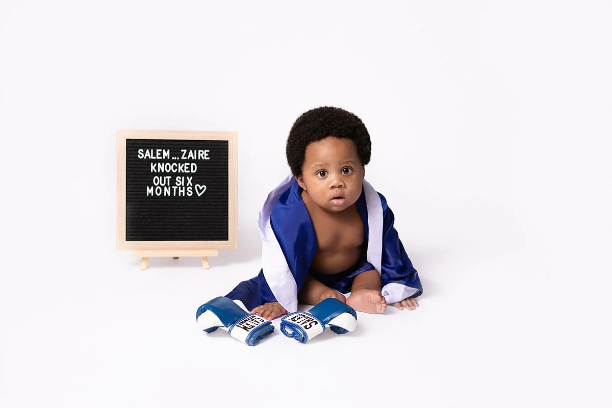 Baby Salem Zaire in a boxing robe beside a half birthday letterboard, 6 month milestone by Sarah Kane Photography, Chesterfield VA
