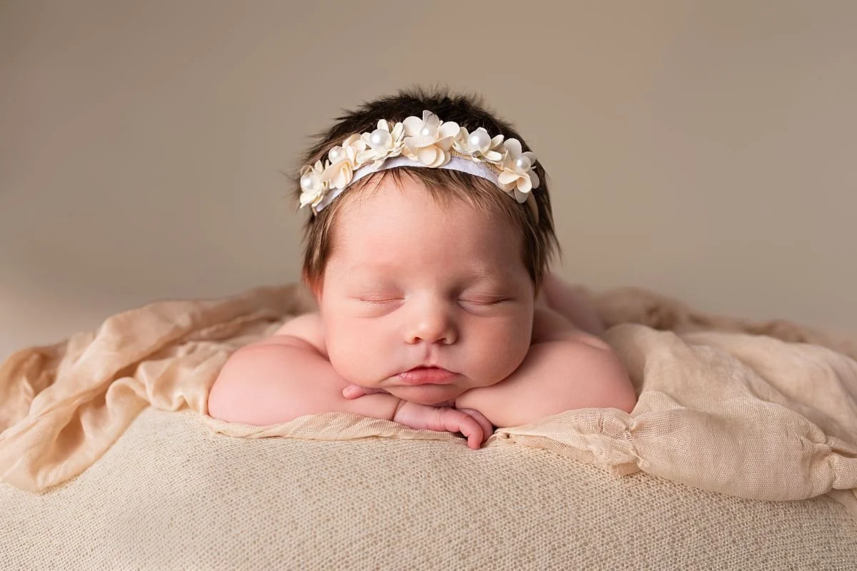 Sleeping newborn baby girl resting chin on her hands with pearl flower headband, Sarah Kane Photography