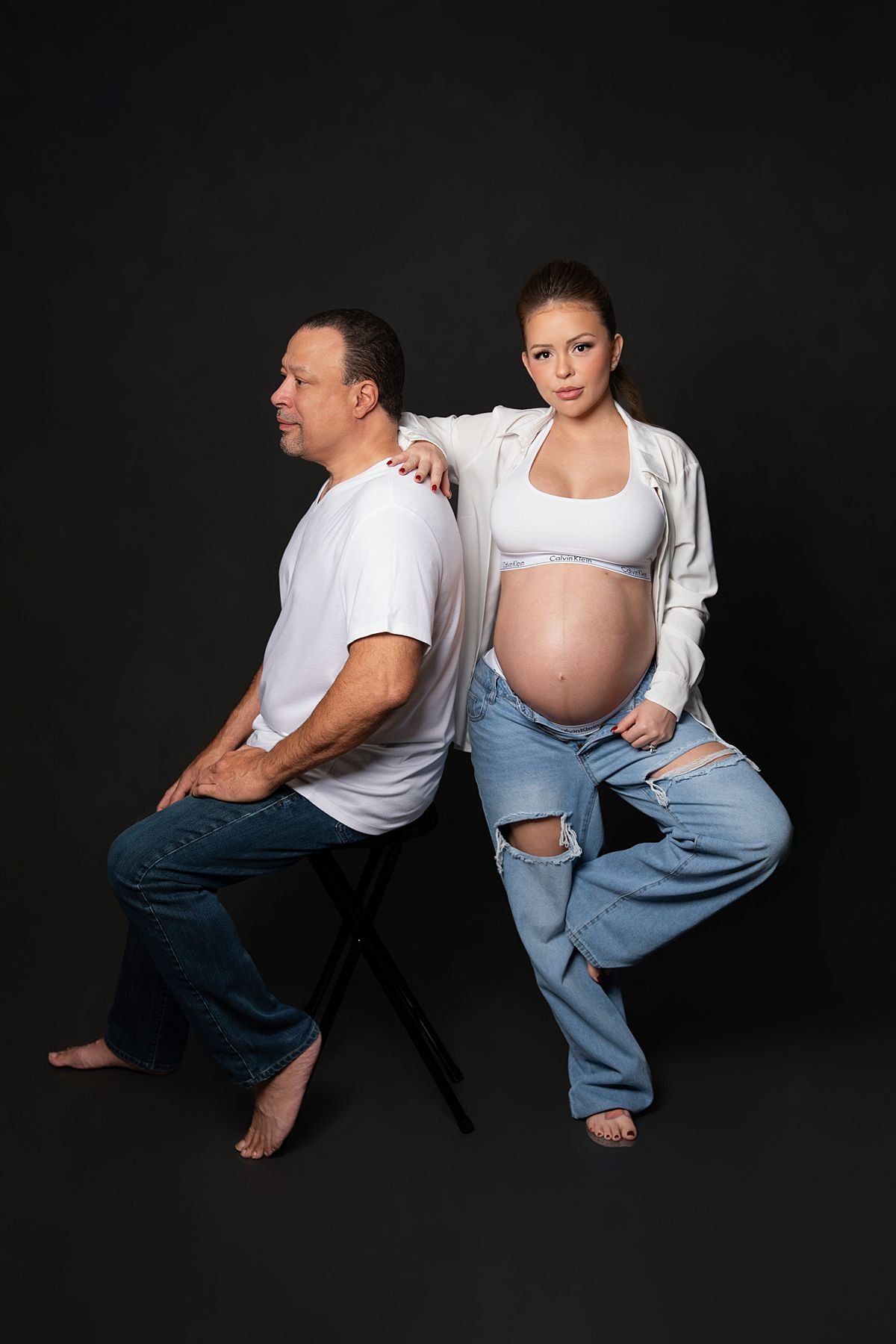 Expecting couple posing together with the woman's arm resting on her partners back, Sarah Kane Photography
