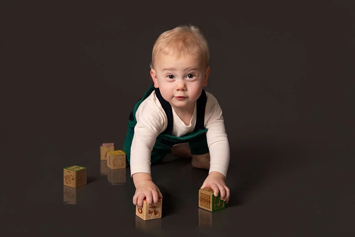 One year old twin crawling with wooden blocks in his hands by Sarah Kane Photography