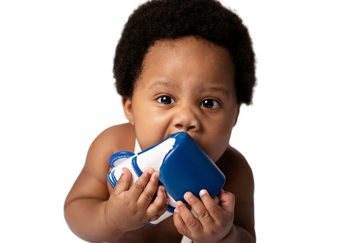 Close up of baby Salem chewing on a blue boxing glove, wide eyed and curious by Sarah Kane Photography, Chesterfield VA
