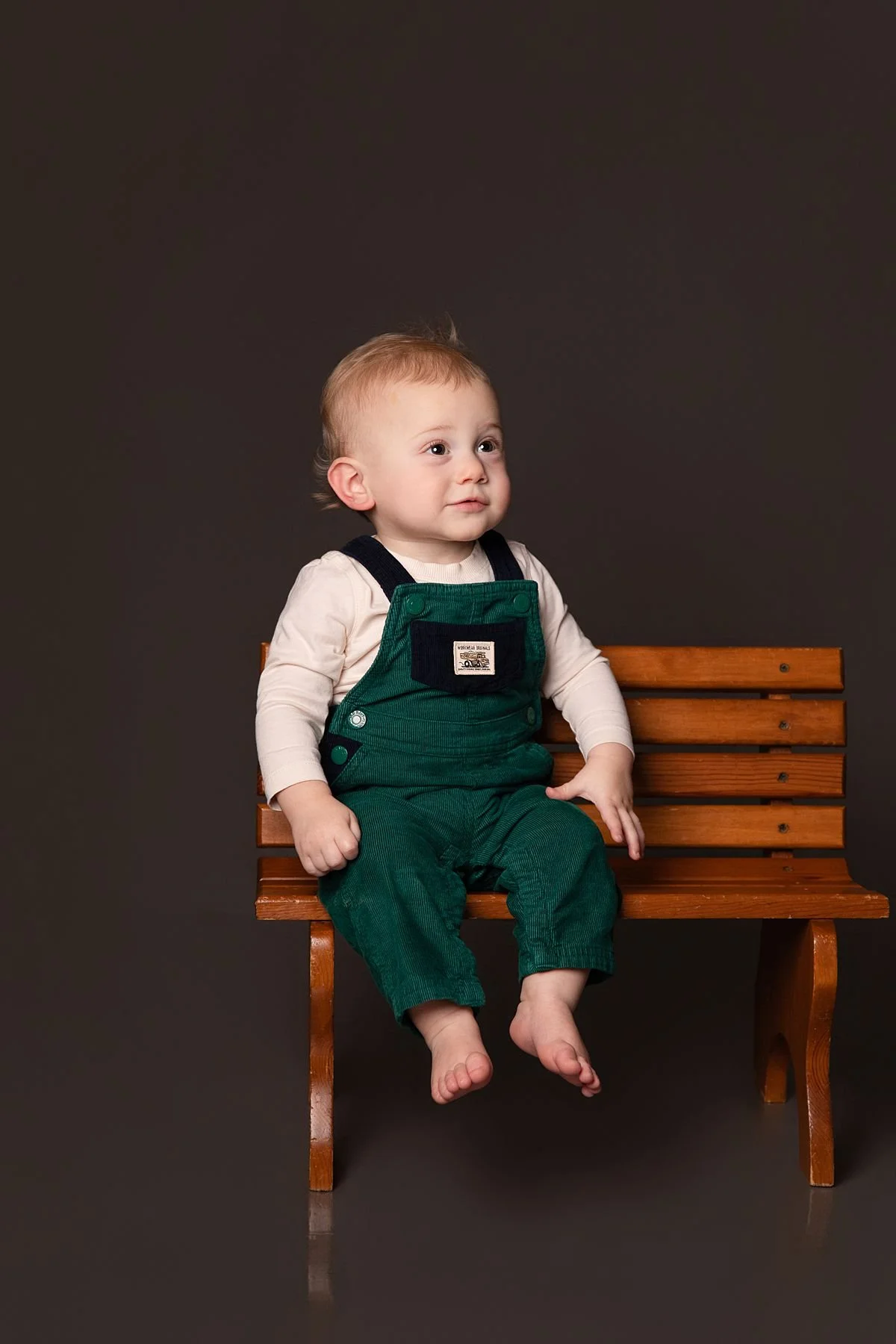 One year old twin sitting alone on a wooden bench by Sarah Kane Photography