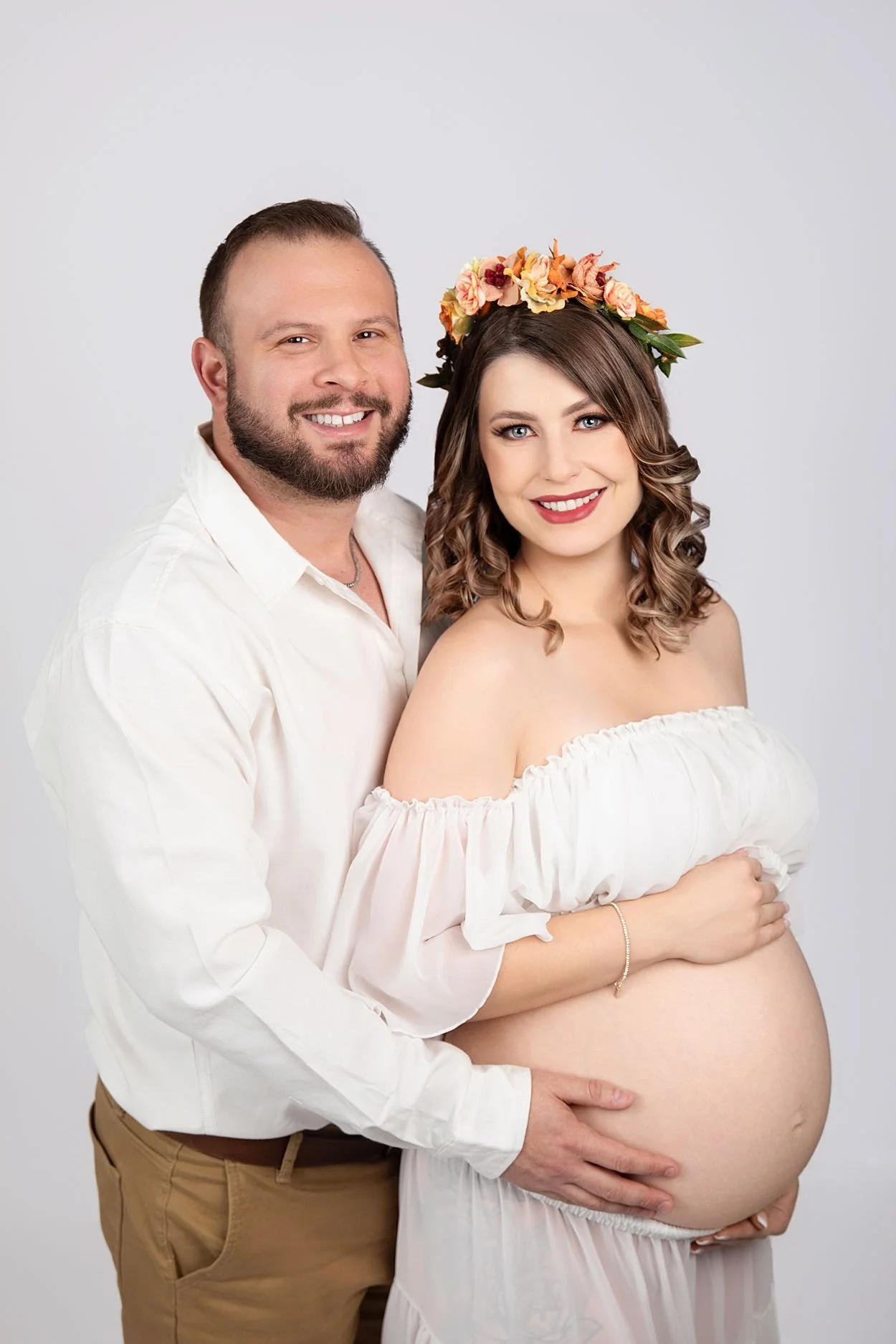 Studio Maternity Photographer in Chesterfield Virginia Just Outside of Williamsburg VA, smiling couple holding her pregnant belly against a neutral backdrop