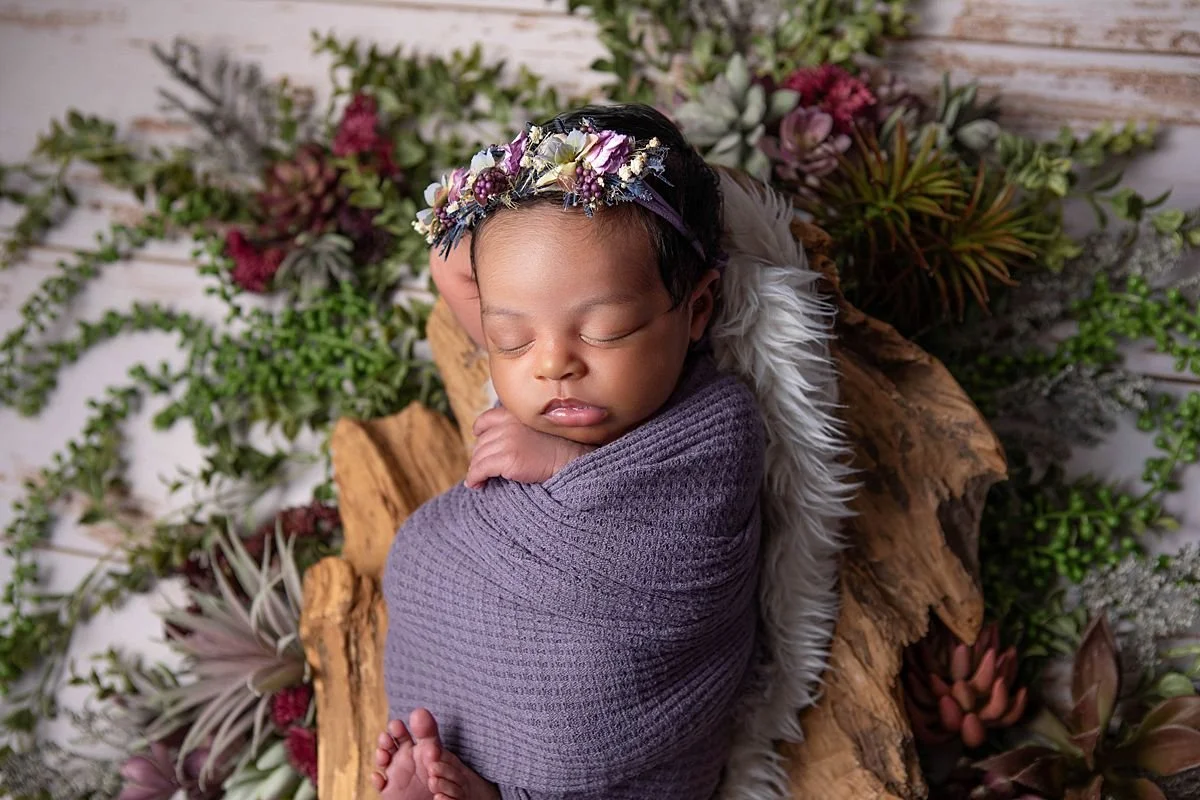 Newborn baby wrapped in purple with floral crown surrounded by greenery in a studio newborn portrait in Chesterfield VA near Richmond by Sarah Kane Photography