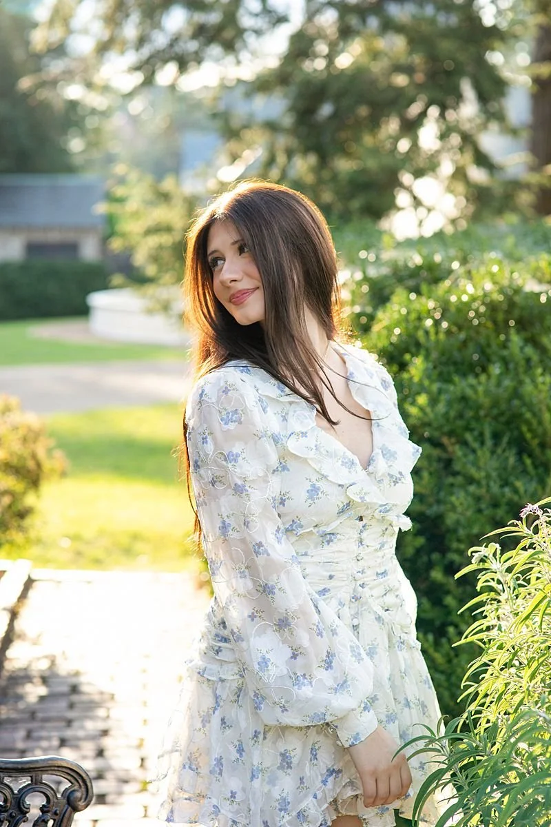 Senior looking over her shoulder in golden hour backlight in a garden at Maymont Park in Richmond  Virginia senior portraits by Sarah Kane Photography