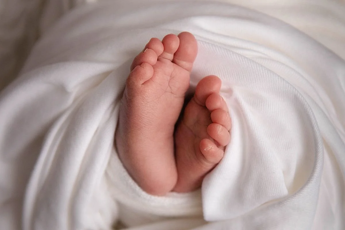 A serene newborn photo featuring baby  feet swaddled in white wraps, resting in a white box surrounded by soft textures in Sarah Kane Photography’s Chesterfield, VA studio close to Mechanicsville.