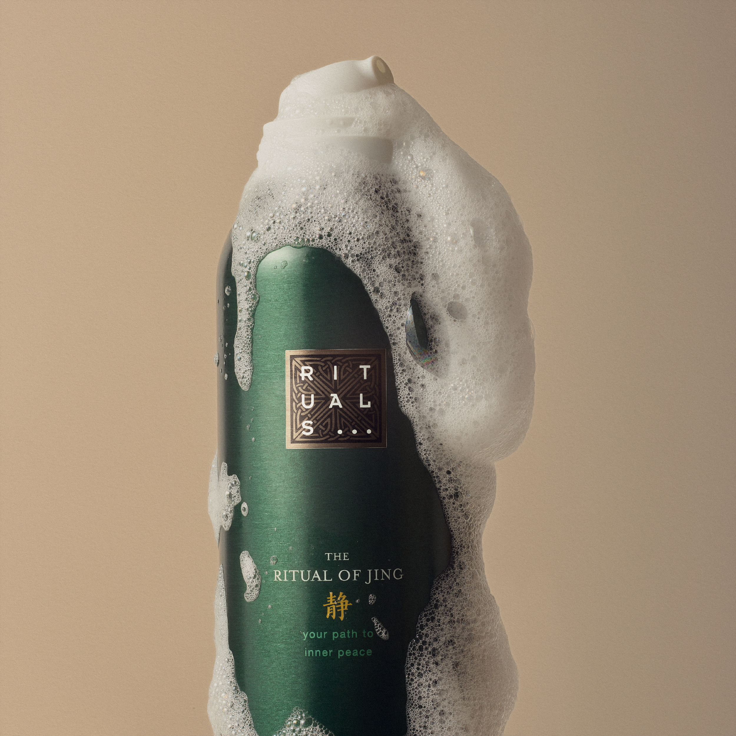 Botella de Rituals The Ritual of Jing cubierta de espuma blanca sobre fondo beige. Foto de Alfonso +Alicia Studio.