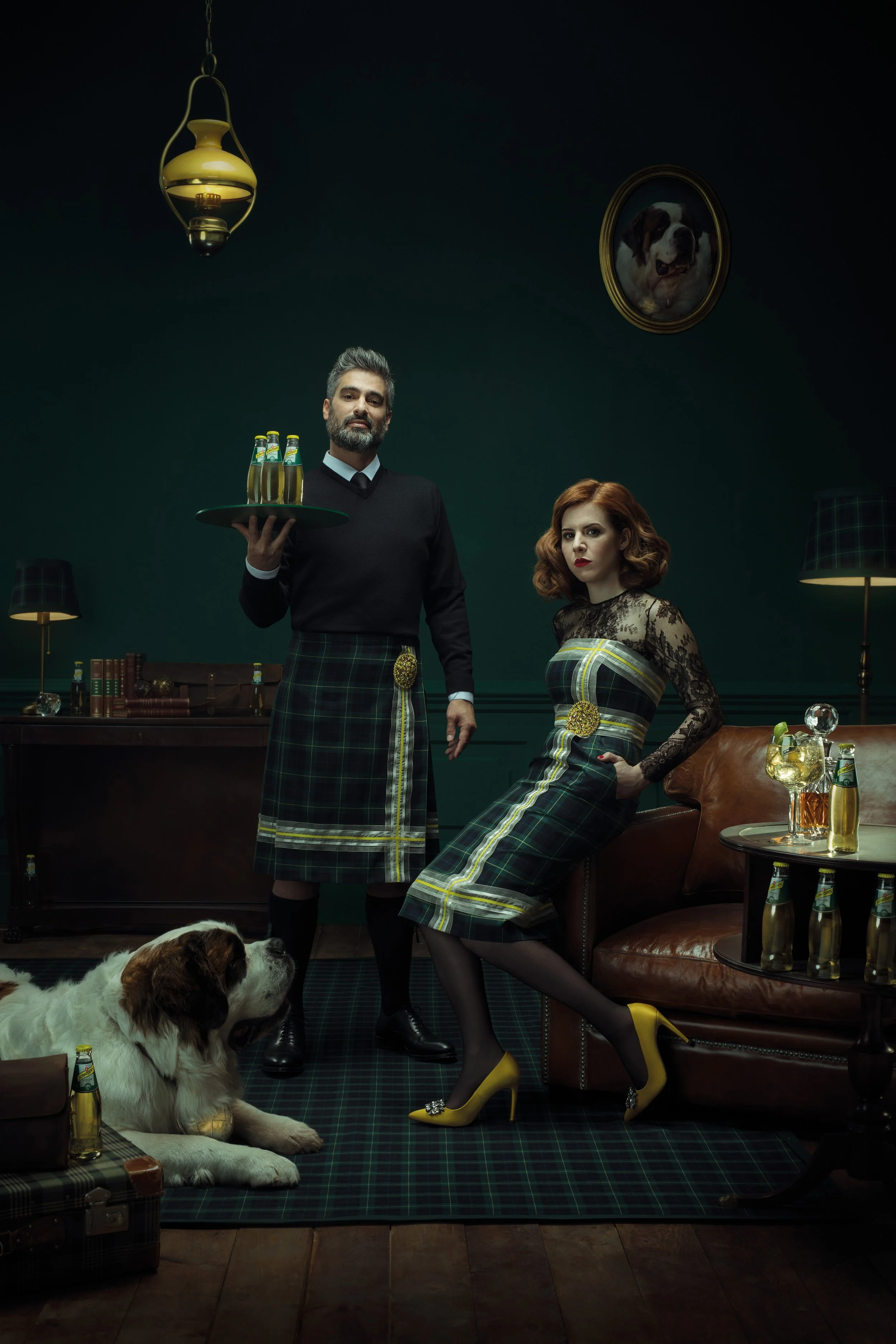 Fotografía publicitaria para Schweppes Ginger Ale — pareja vestida con tartán escocés junto a un perro San Bernardo en un salón clásico con botellas de Schweppes -  Alfonso + Alicia Studio - Alfonso Herranz -
