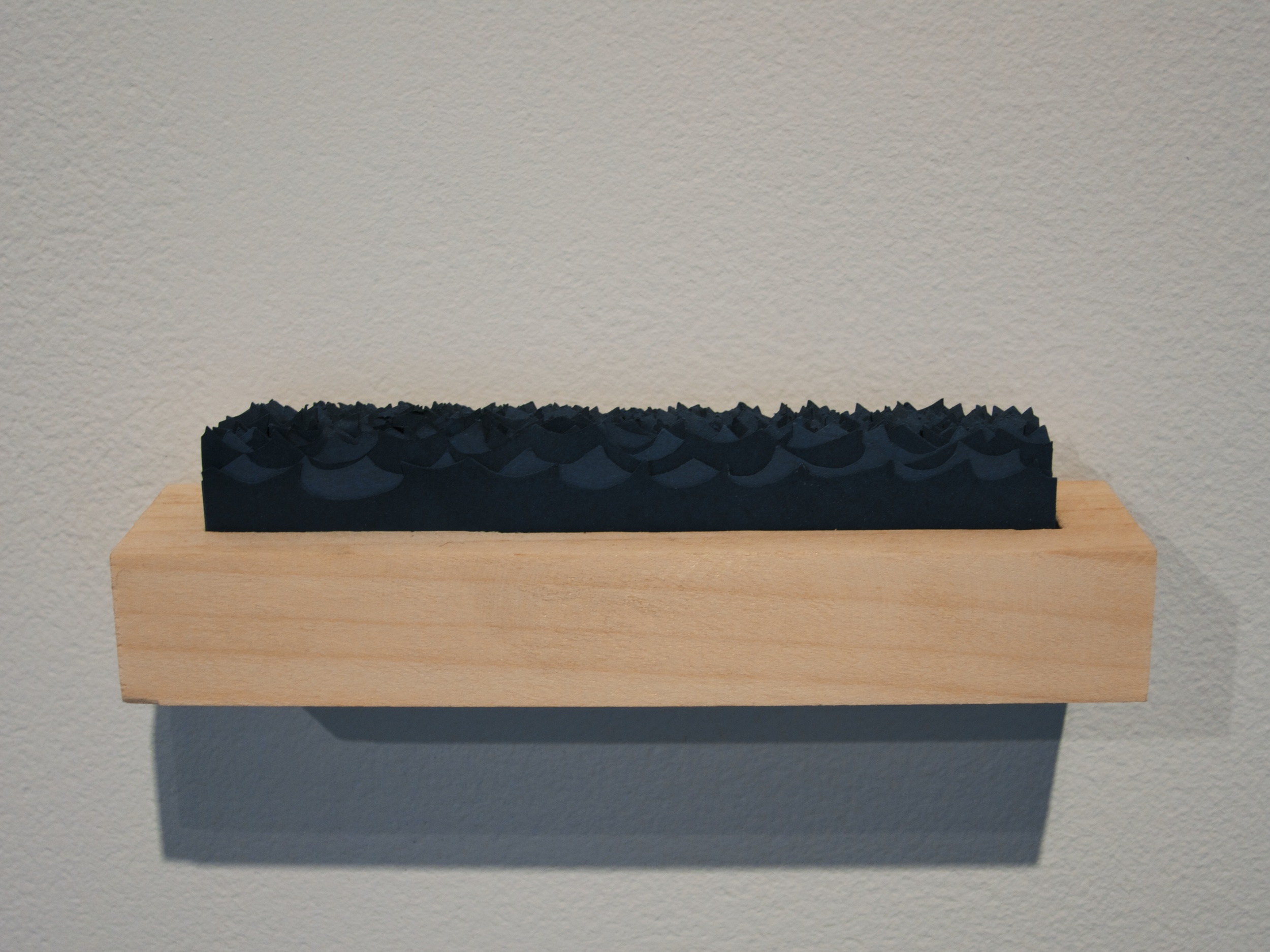  Carved wooden box containing stacked cut paper waves, 6x1x1 inch, 2014. 