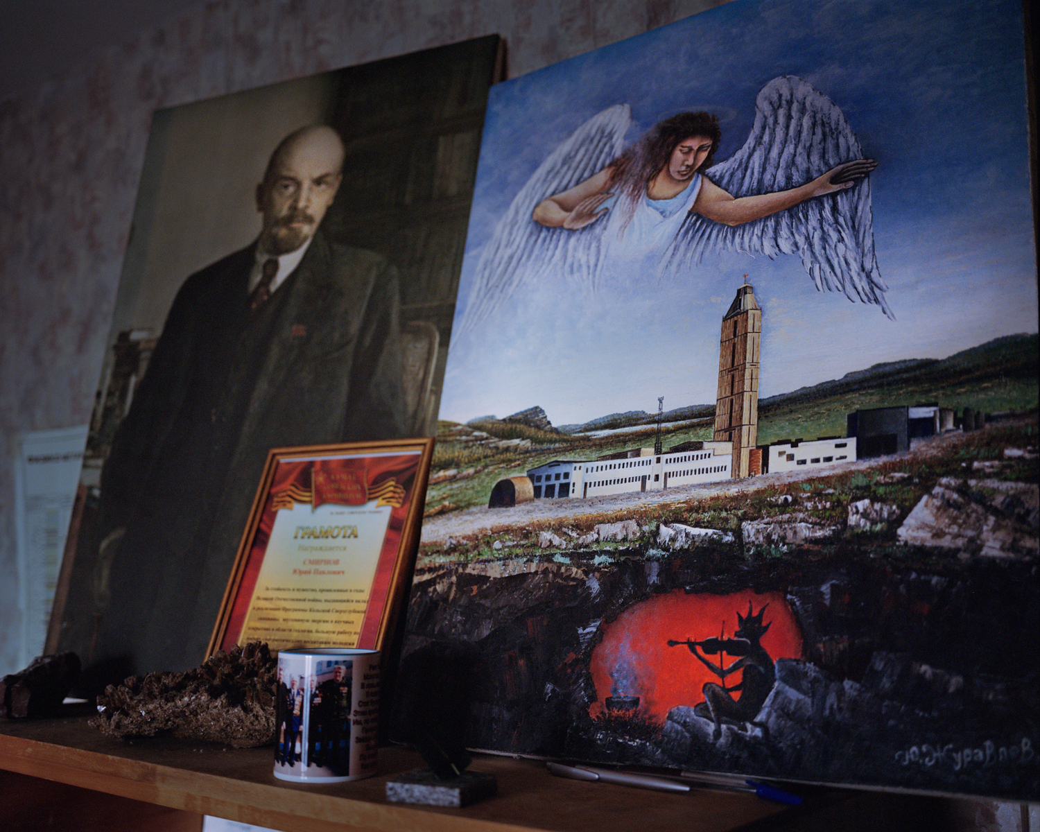 Smirnov displayed a portrait of Lenin, left, next to a painting depicting the urban legend that the sounds of hell could be heard coming from the bottom of the borehole.