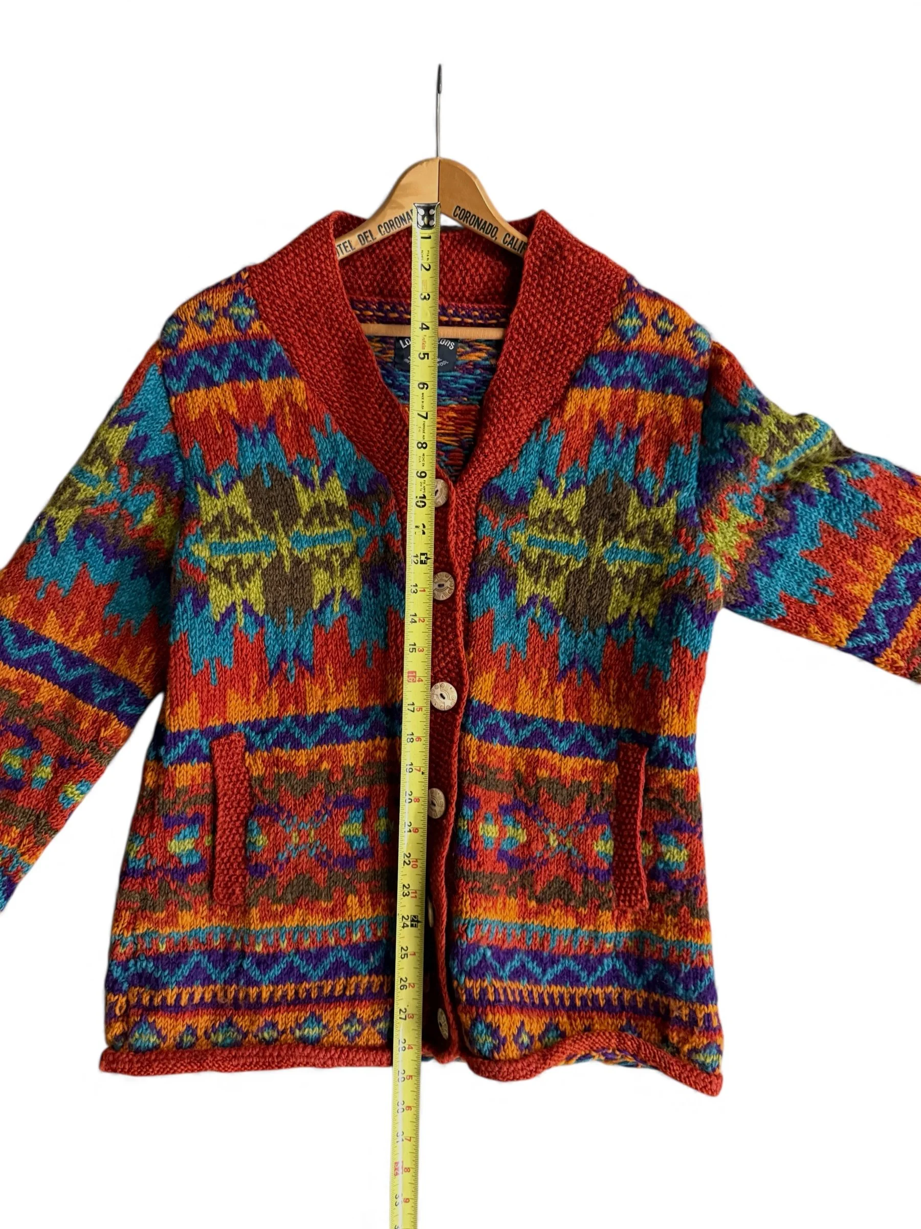 Flat view of colorful vintage hand knit wool sweater with a ruler showing the length to neck measurements