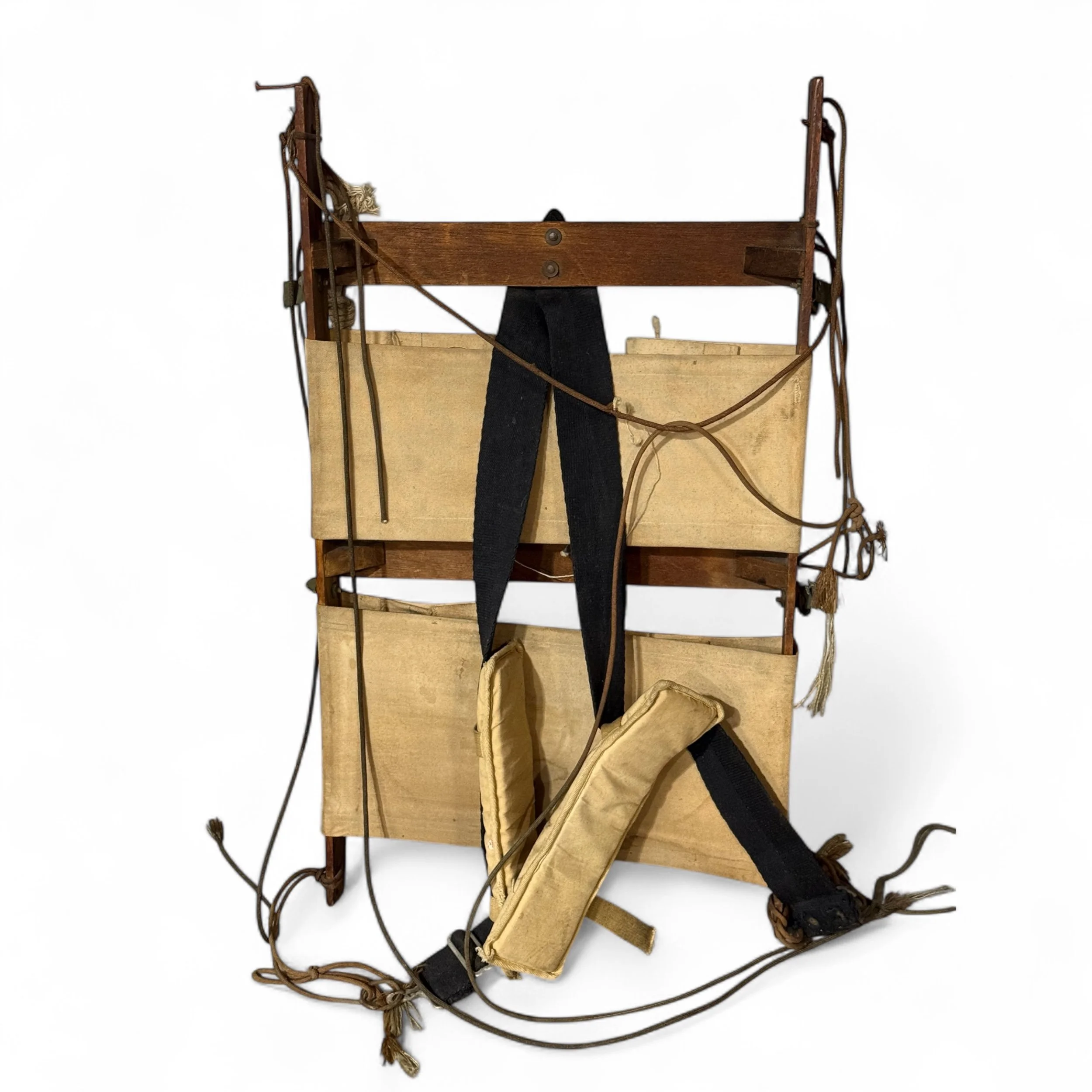 Back view of a vintage wood packboard showing the padding straps and rope details