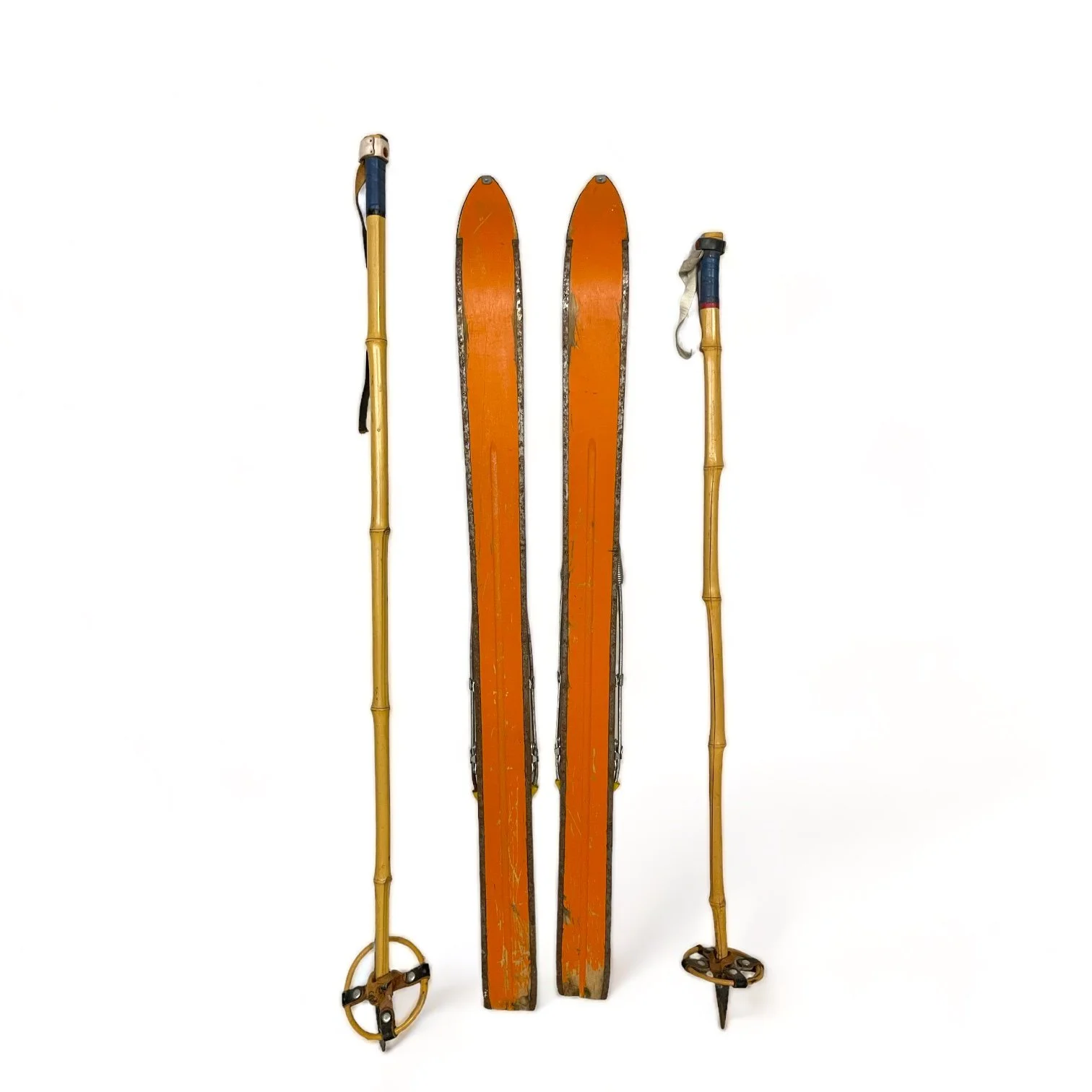 Back view of a pair of vintage kids snow skis with metal bindings and bamboo ski poles, perfect for winter cabin or lodge decor.
