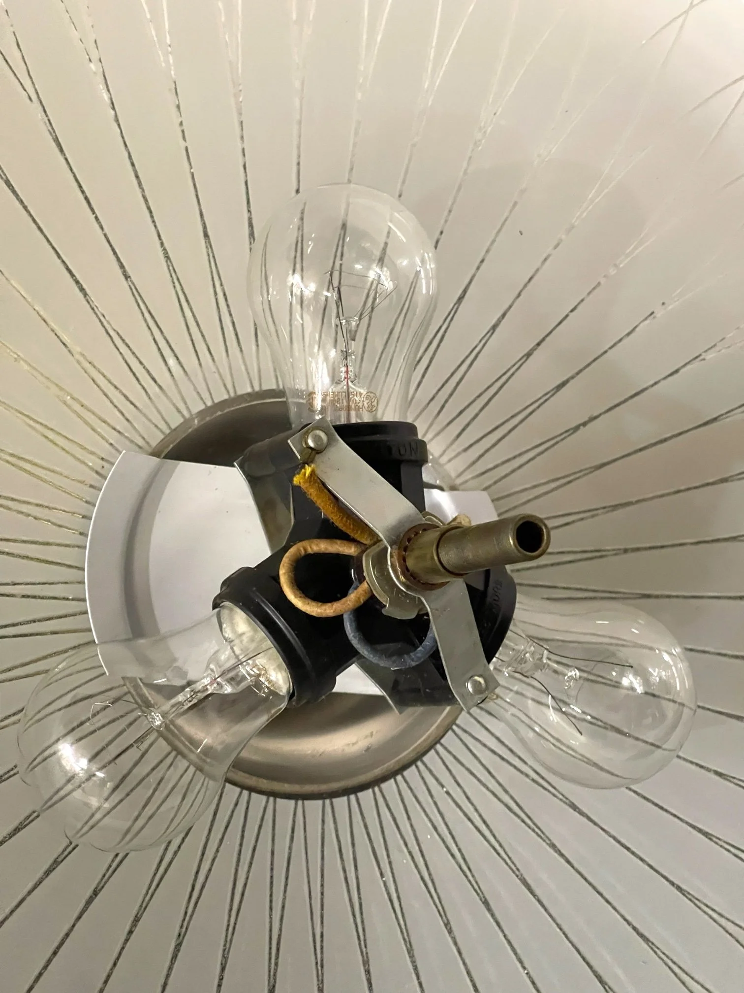 Close up of a vintage glass atomic saucer hanging ceiling light with 3 light sockets, showcasing its mid century modern design and sleek glass shade, perfect for retro and modernism decor.