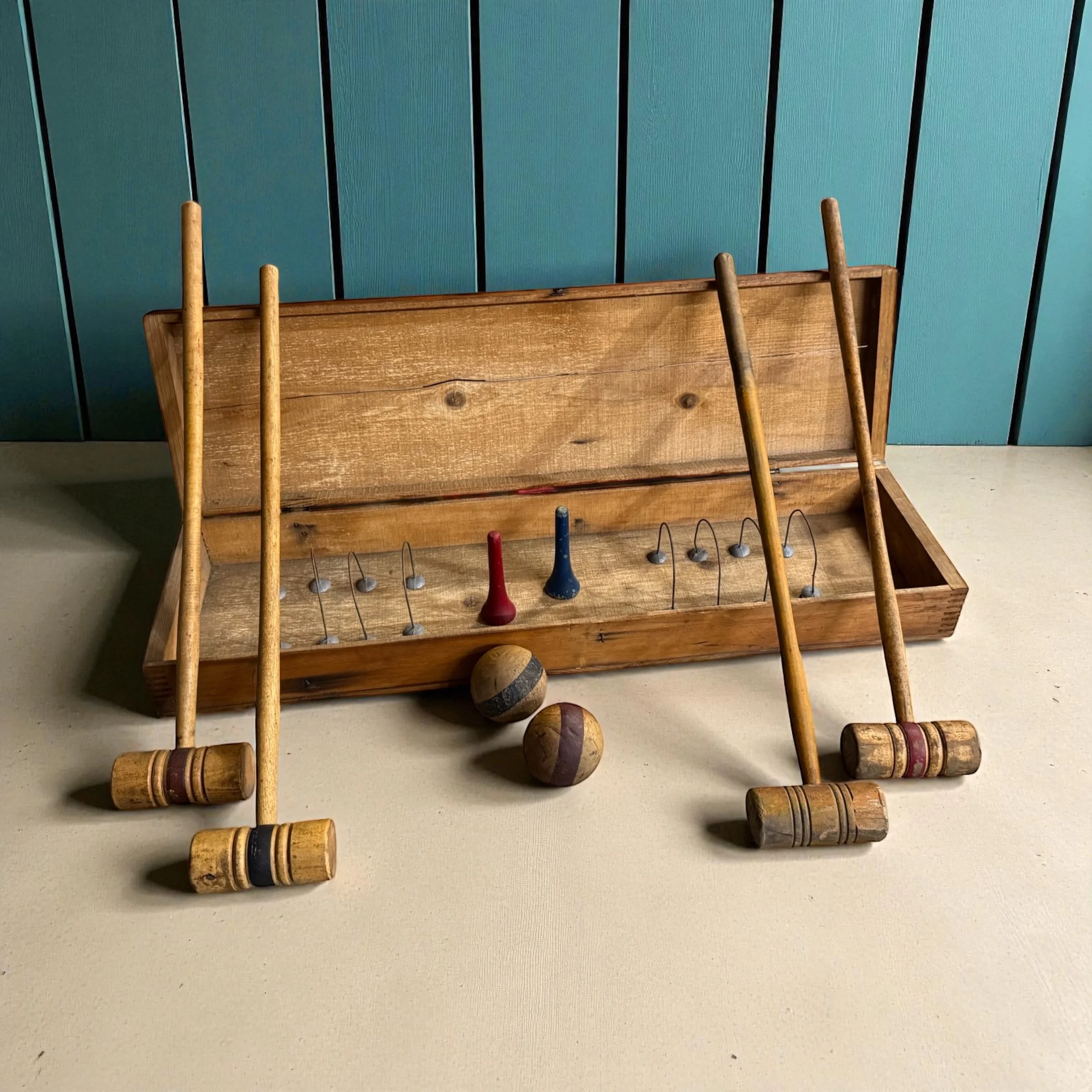 Vintage croquet set arranged for decor styling with a turquoise wall in the background