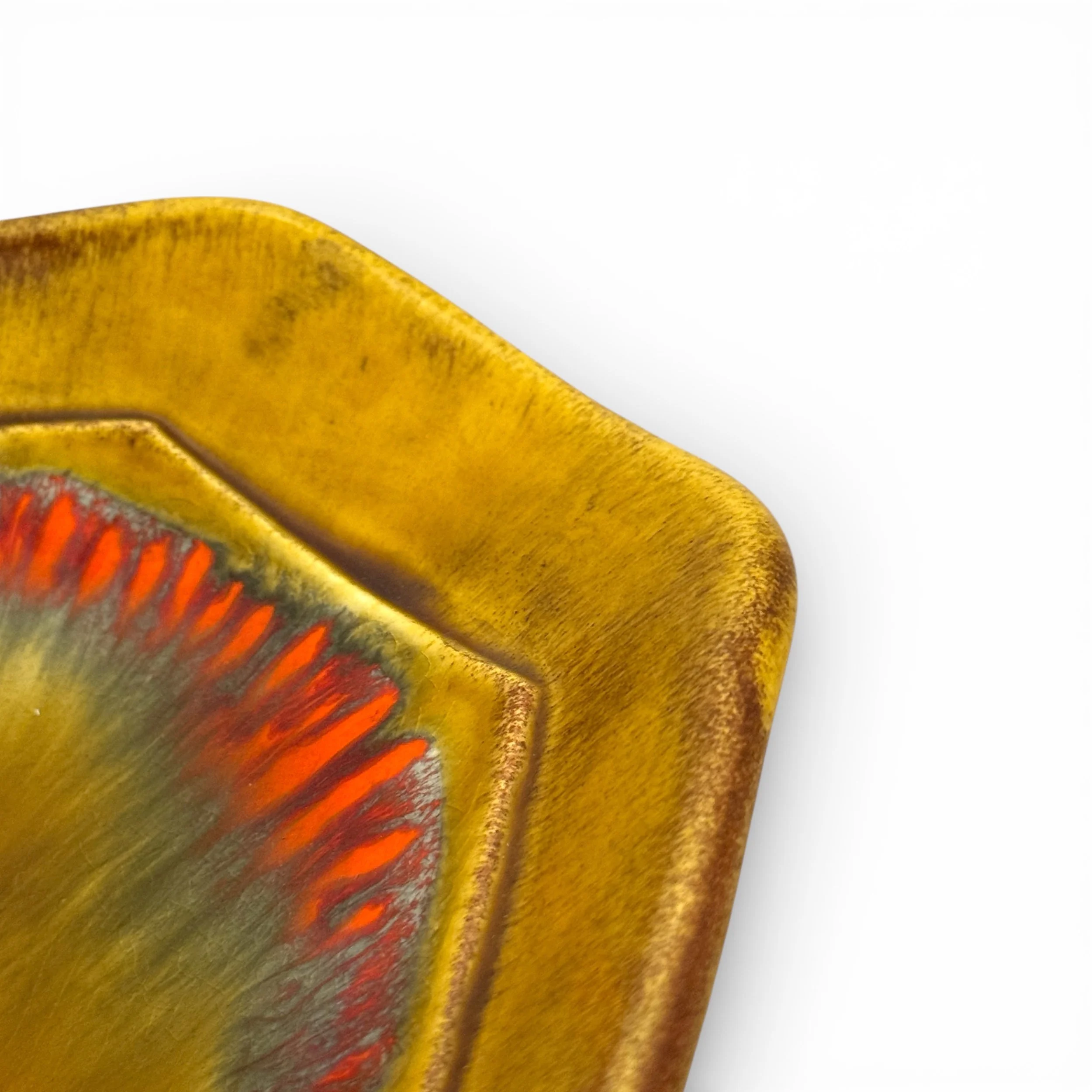 Close up view of a vintage mid century glazed ceramic decorative dish, featuring rounded corners, unique shape, colorful palette of goldenrod, red, and green