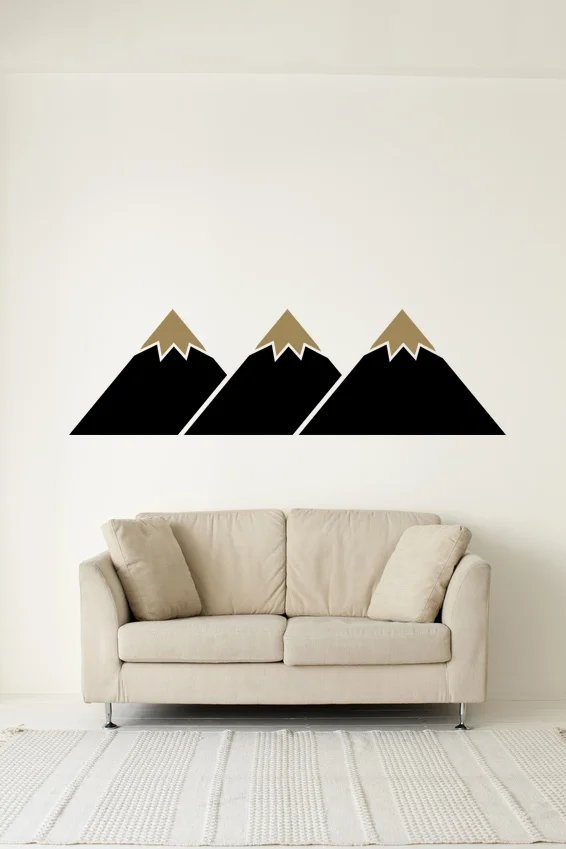 A two color geometric minimalist mountain range wall decal styled on a wall above a couch in a modern living room.