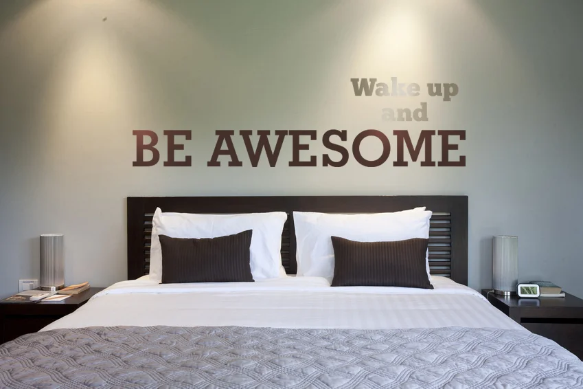 Wake up and be awesome wall decal installed in a modern minimalist bedroom.