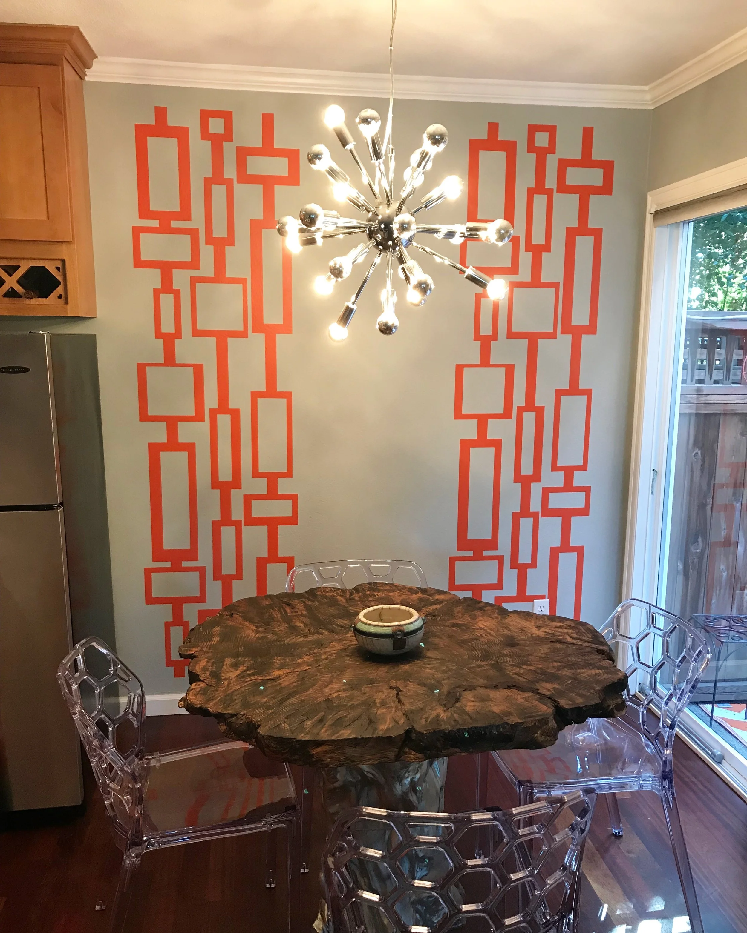 Mid Century geometric rectangle and square wall decal pattern shown in orange on a light grey wall in a modern dining room.