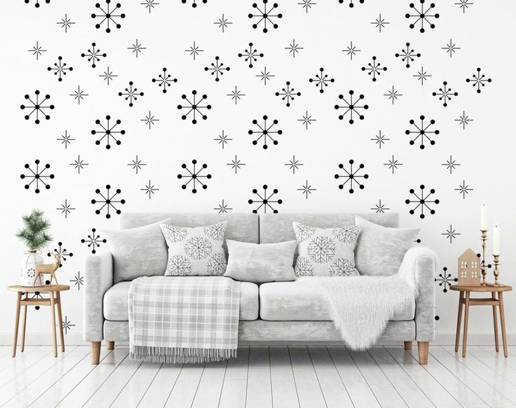 Retro atomic starburst pattern wall decals in dark grey on a white wall behind a light grey couch in a mid century styled living room.