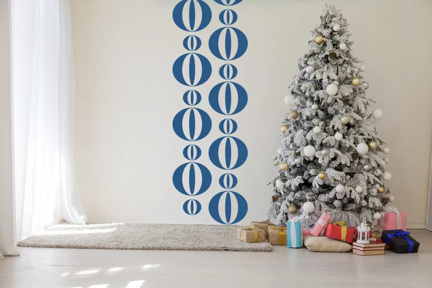A modern and circle geometric wall decal in blue on a white wall behind a retro modern style Christmas tree.