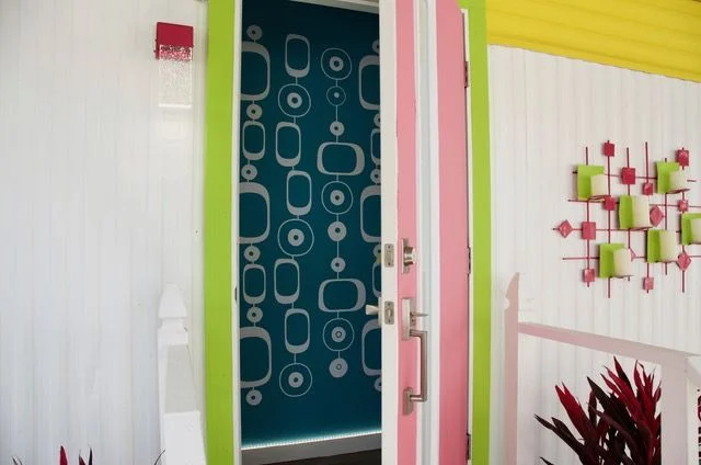 Exterior view of white geometric circle chain wall decal by Wall Star Graphics, turquoise painted wall in hallway, colorful mid century exterior trailer.