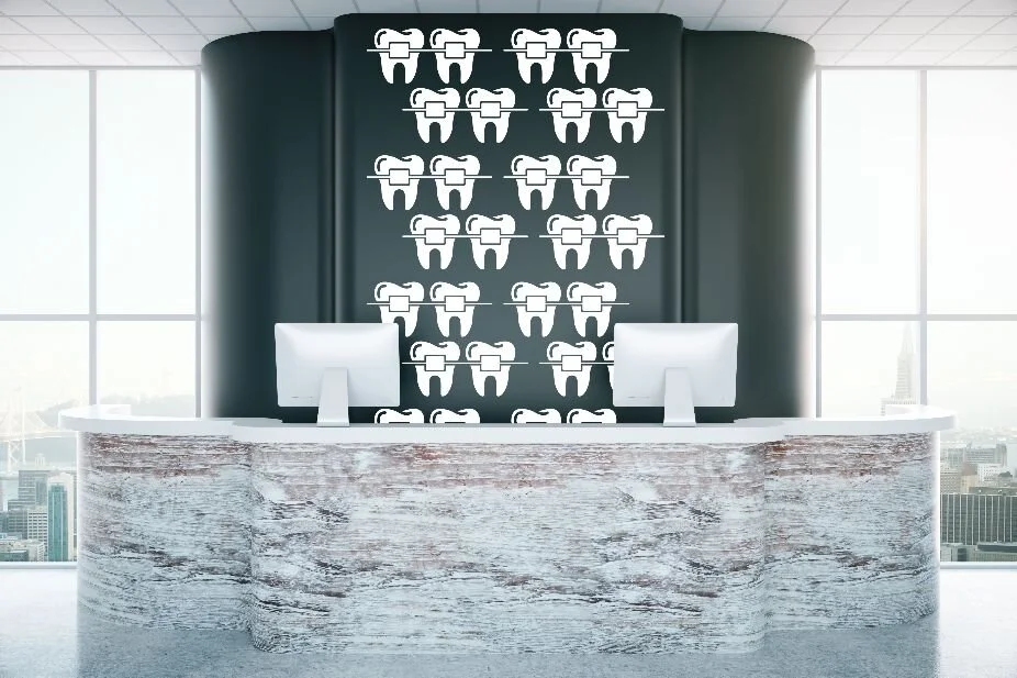 Teeth with braces wall decal for orthodontist and dentist office decor shown on a black wall of a modern office lobby.