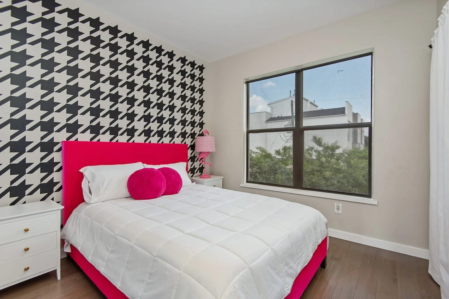 Black houndstooth wall decals installed on a white wall of a mid century style primary bedroom of a vacation rental.