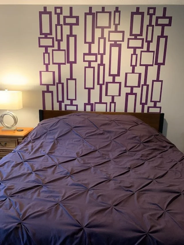 Mid Century geometric rectangle and square wall decal pattern shown in purple on a white wall in a bedroom.