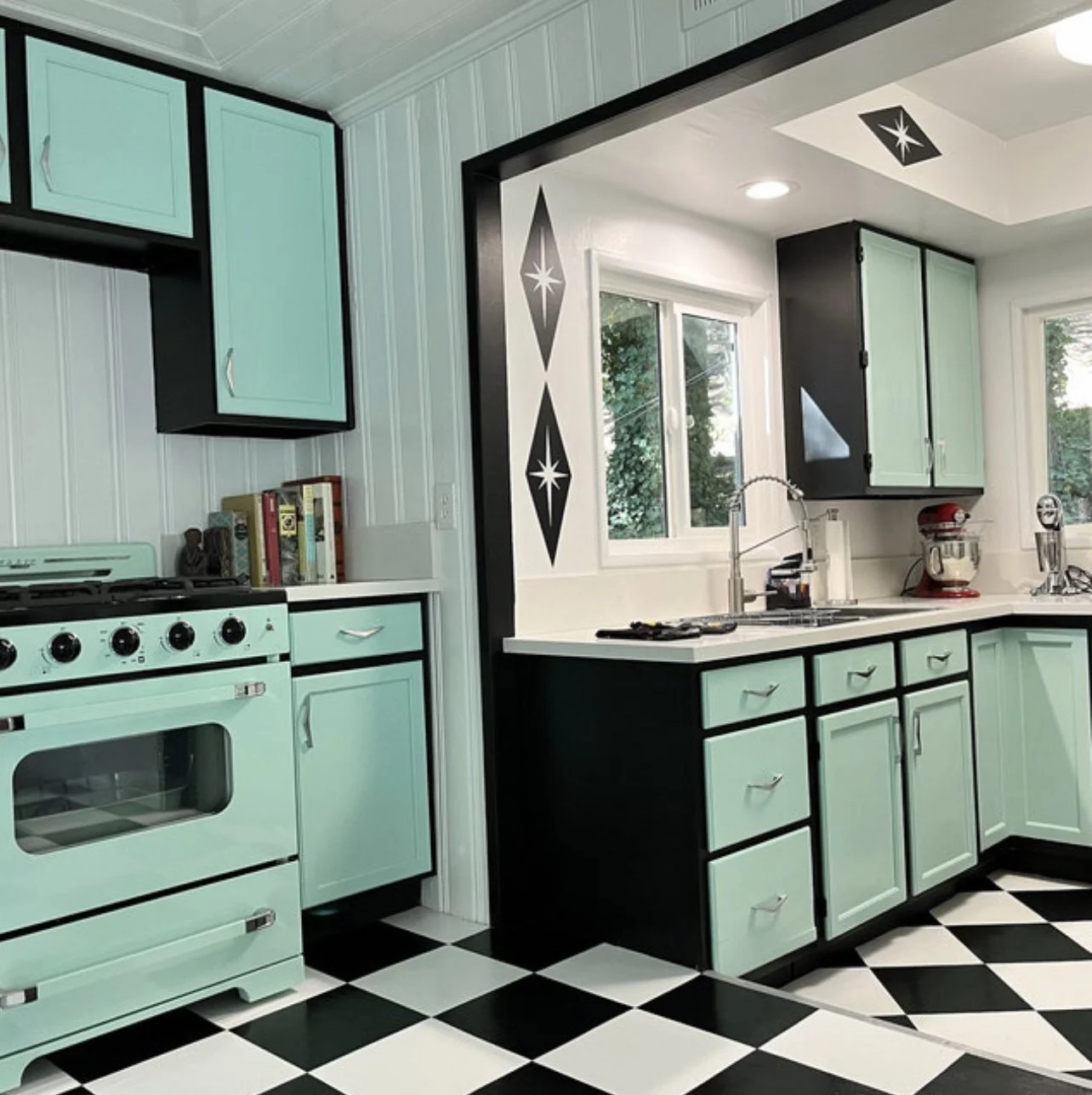 Mid century atomic style wall decals consisting of large diamond shapes with atomic stars shown in black on a white wall of a retro black, white, and mint green kitchen.