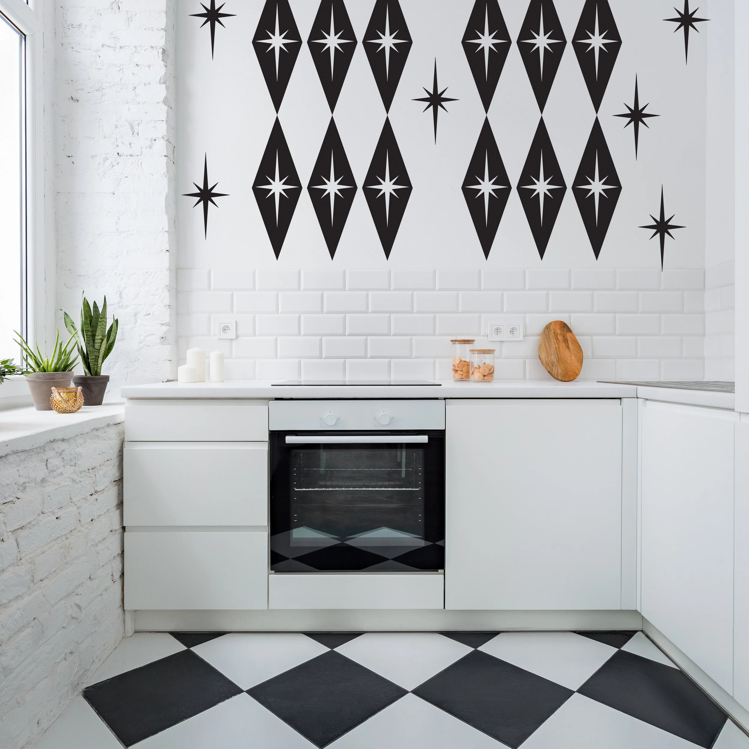 Mid century atomic style wall decals consisting of large diamond shapes with atomic stars shown in black on a white wall of a retro black and white kitchen.