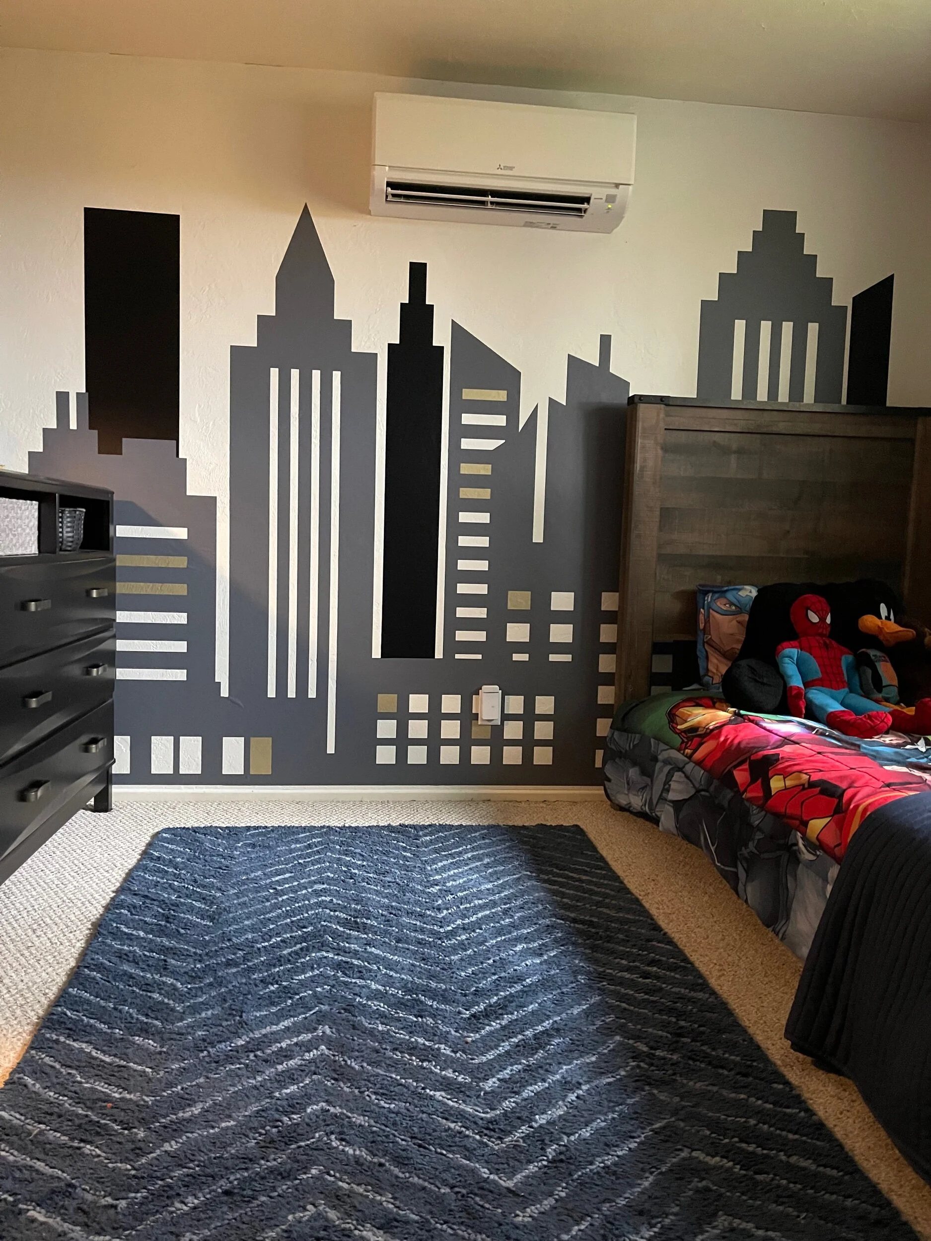 Large city skyline wall decal shown on a white wall of a modern kids bedroom for hero themed decor.