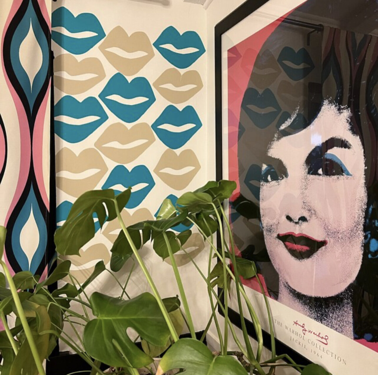 Lip wall decals in turquoise and beige in stalled on a white wall next to a Jackie O framed poster.