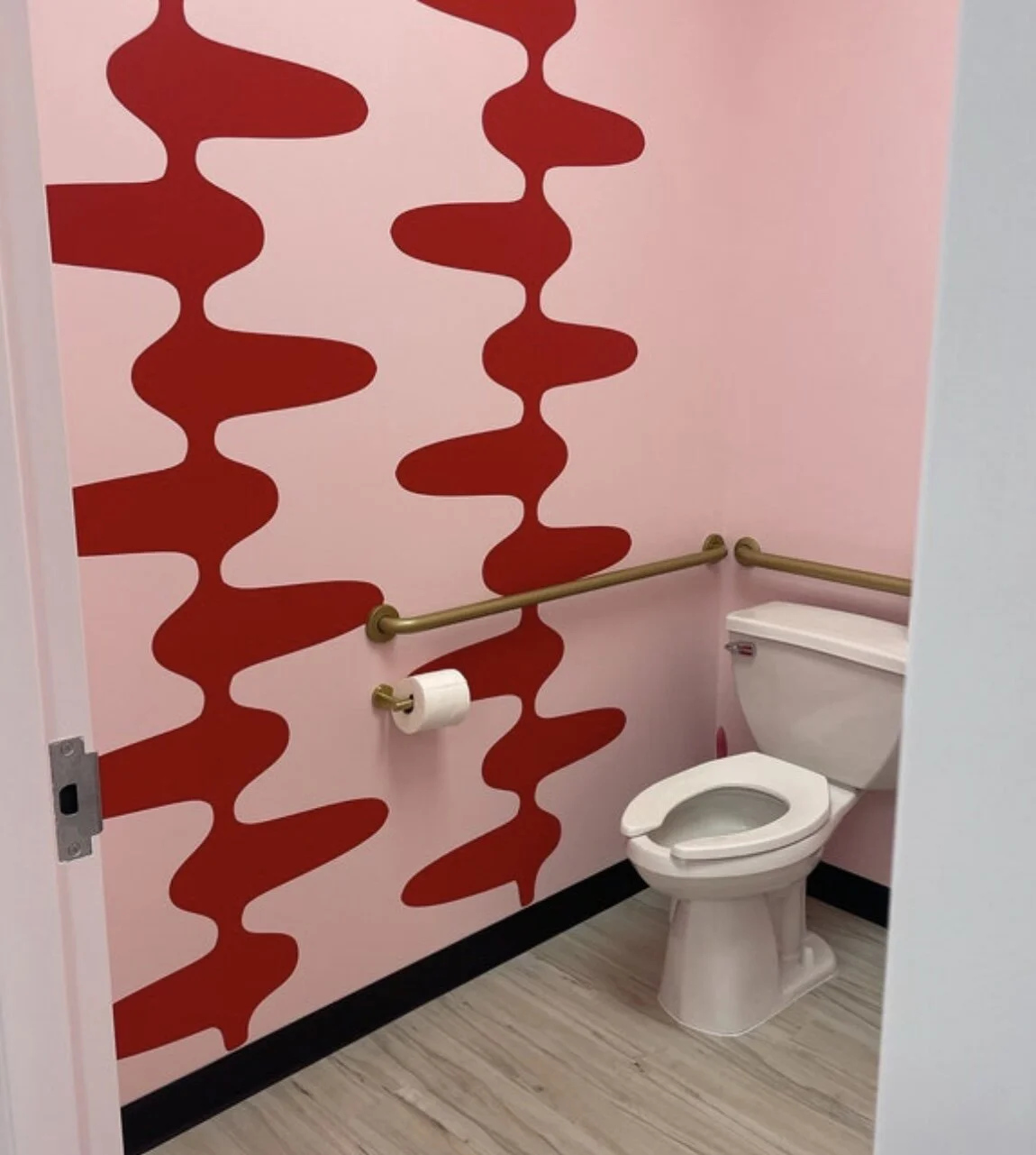 Retro and mid century inspired geometric wall decal pattern shown in red on a pink wall in a modern bathroom.
